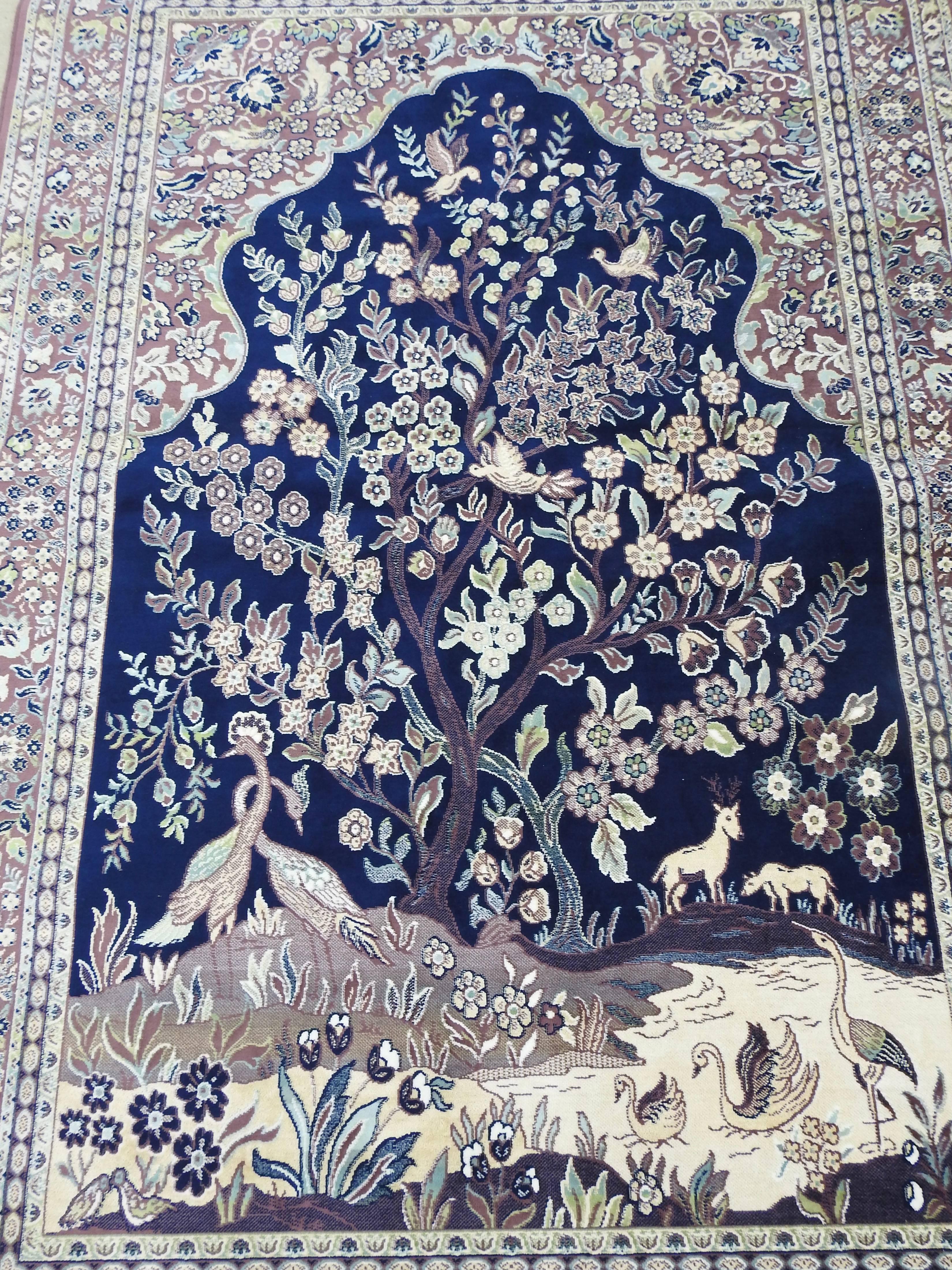 Soft shades of navy blue, lavender and cream make this rug a beautiful melody of silk. Flowers, trees and a variety of animals are surrounded by a decorative border. There is fringe on the ends to complete the look. A rod pocket has been added to