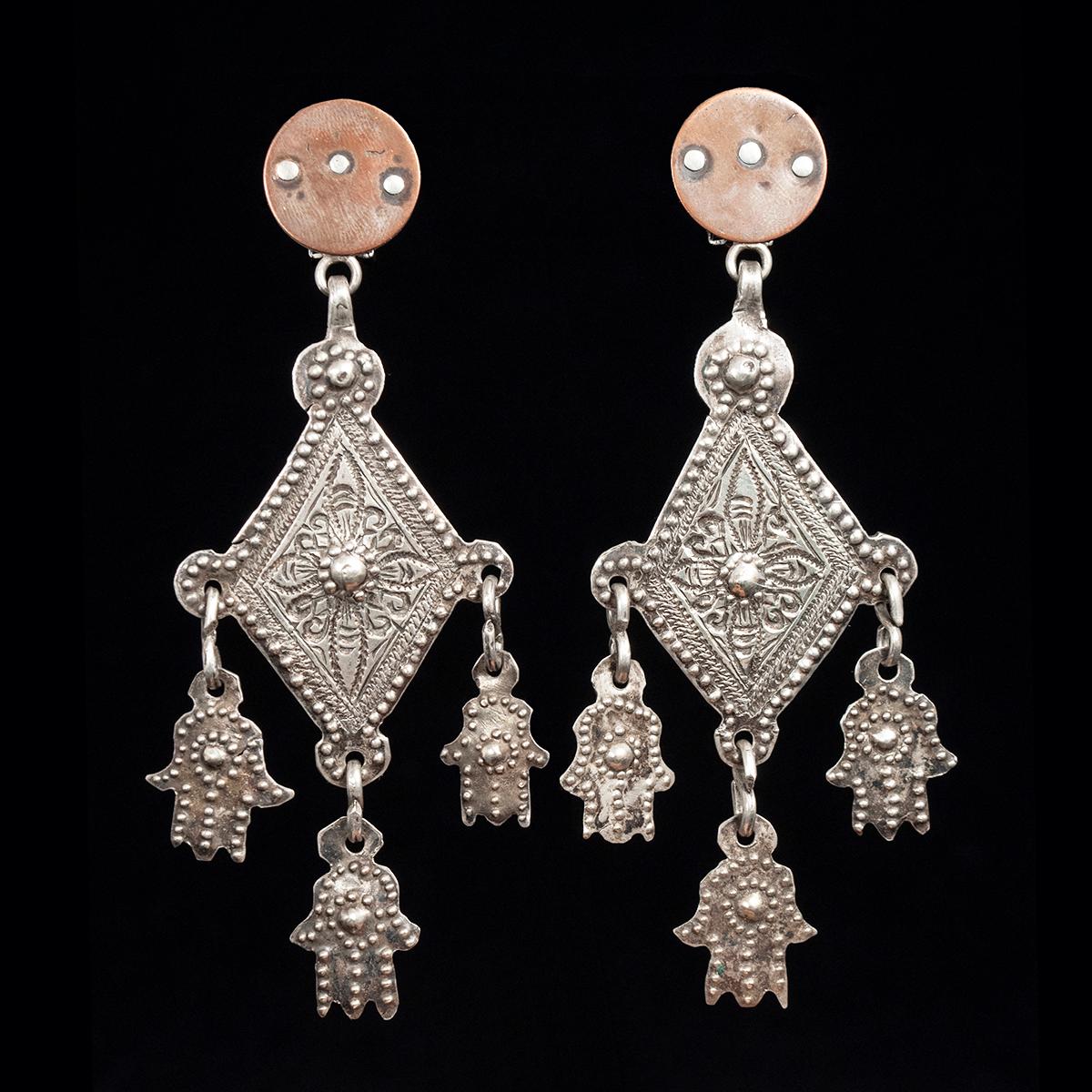 Mid-20th Century Silver Khamsa and Copper Earrings by Jewels of Santa Fe/Marrakesh

A pair of earrings made by Jewels with rural Moroccan village pendants with three small khamsas, hung from her signature hand made disks, these in copper.
They are