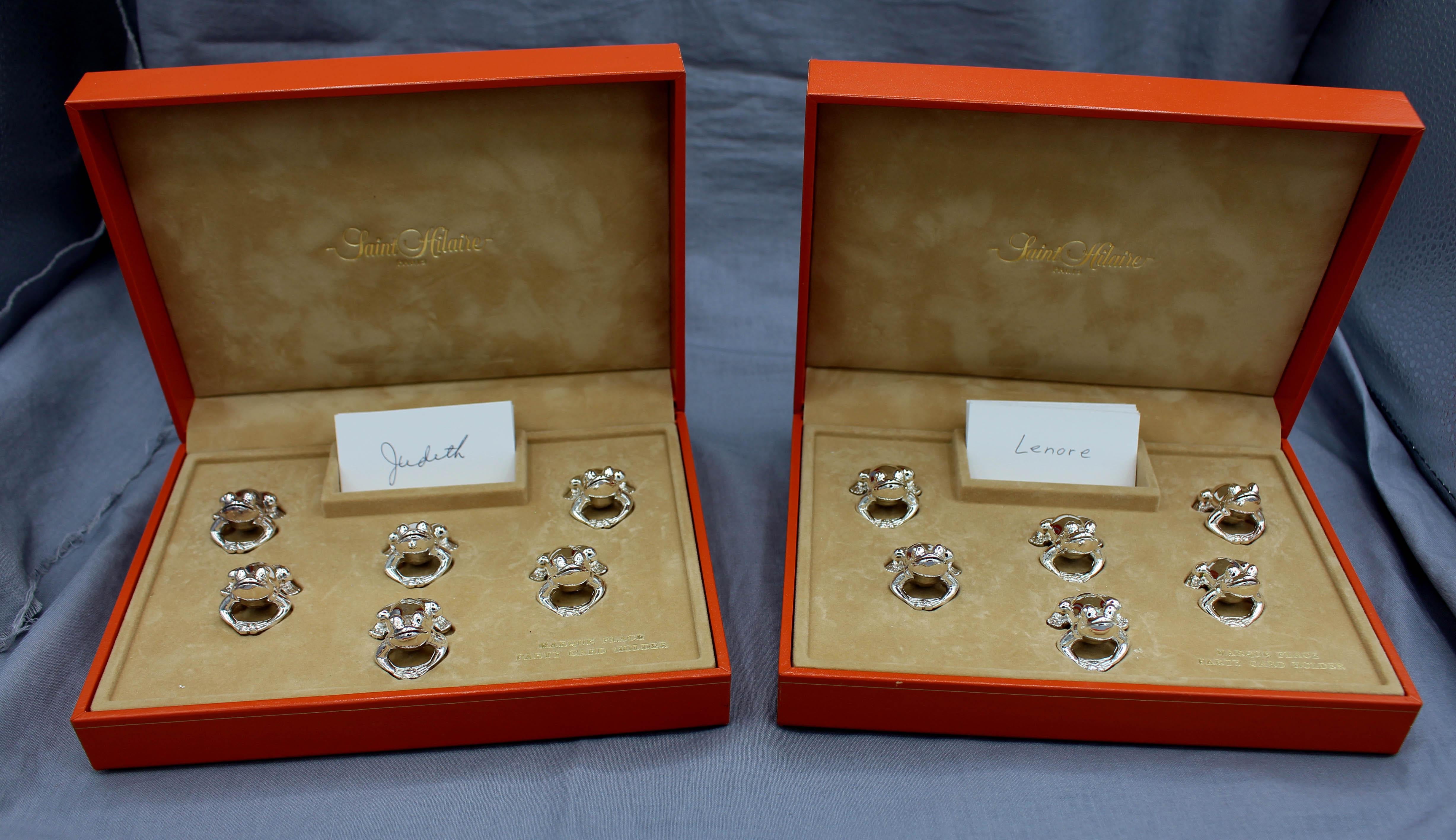 Mid-20th century set of 12 silver plated frog place card holders from St. Hilaire, Paris in 2 original presentation cases. Estate of Linda Kornberg with names going back to the 1970s parties! One of Paris's most distinctive shops. Made by