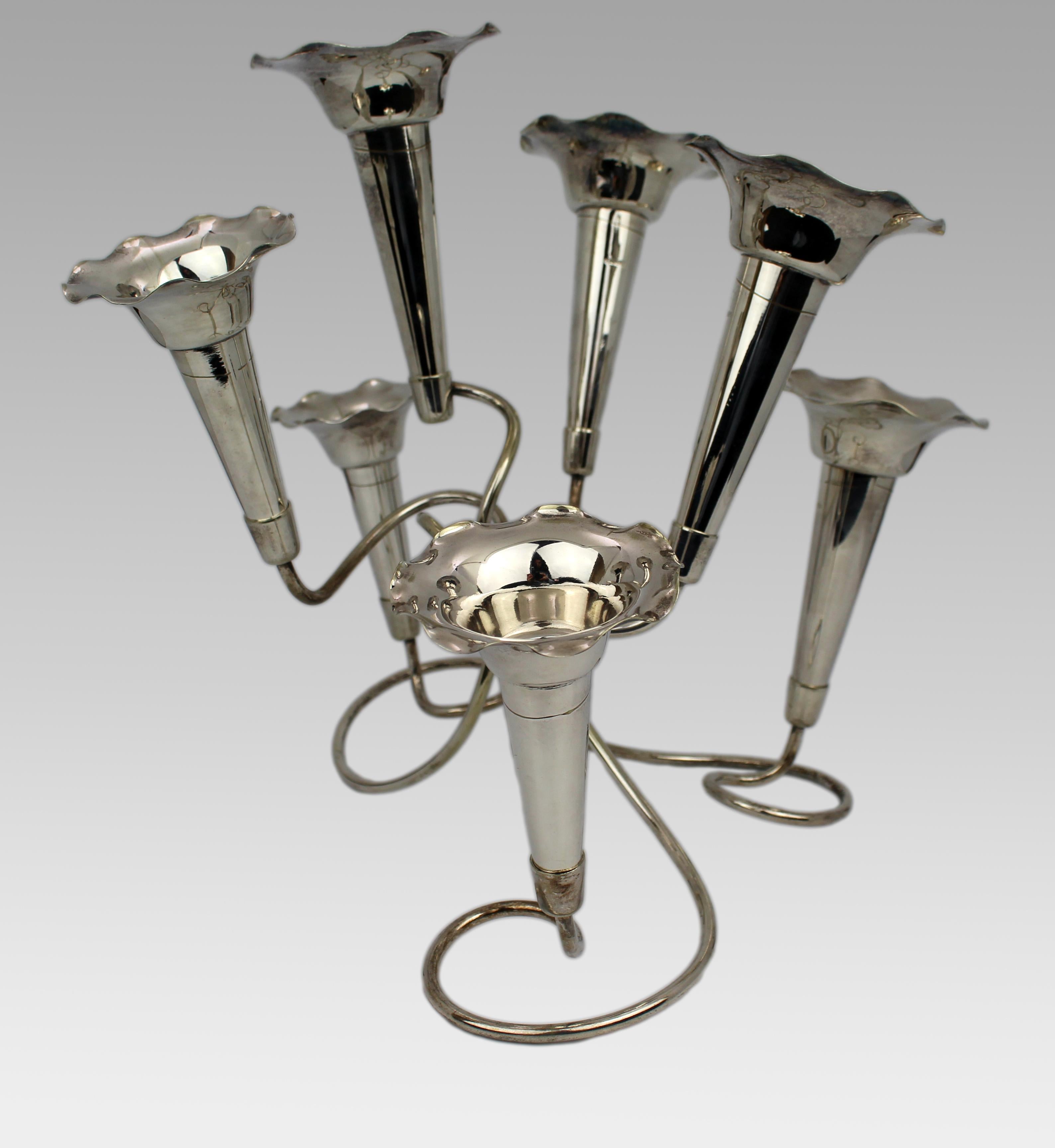 Centre de table en argent à sept trompettes pour l'Epergne du milieu du 20e siècle
La vente porte sur une élégante épergne plaquée argent du milieu du XXe siècle, composée de sept vases détachables en forme de trompette, disposés de manière florale