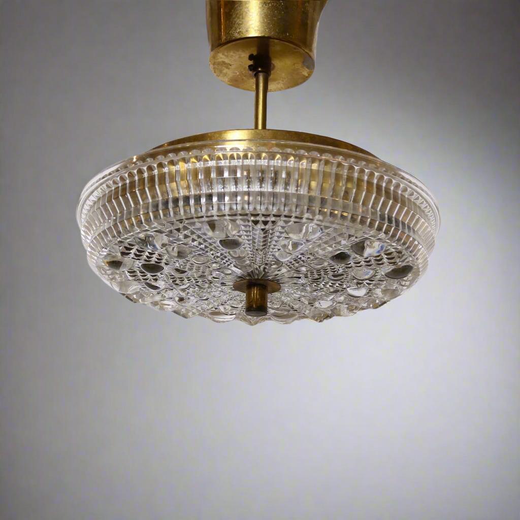 Lampada a sospensione a stelo singolo in vetro fuso con accessori in ottone attribuita a Carl Fagerlund per Orrefors.  Il vetro è stampato con un motivo a rombi in rilievo sulla superficie esterna. L'apparecchio contiene tre lampade a candelabro. 