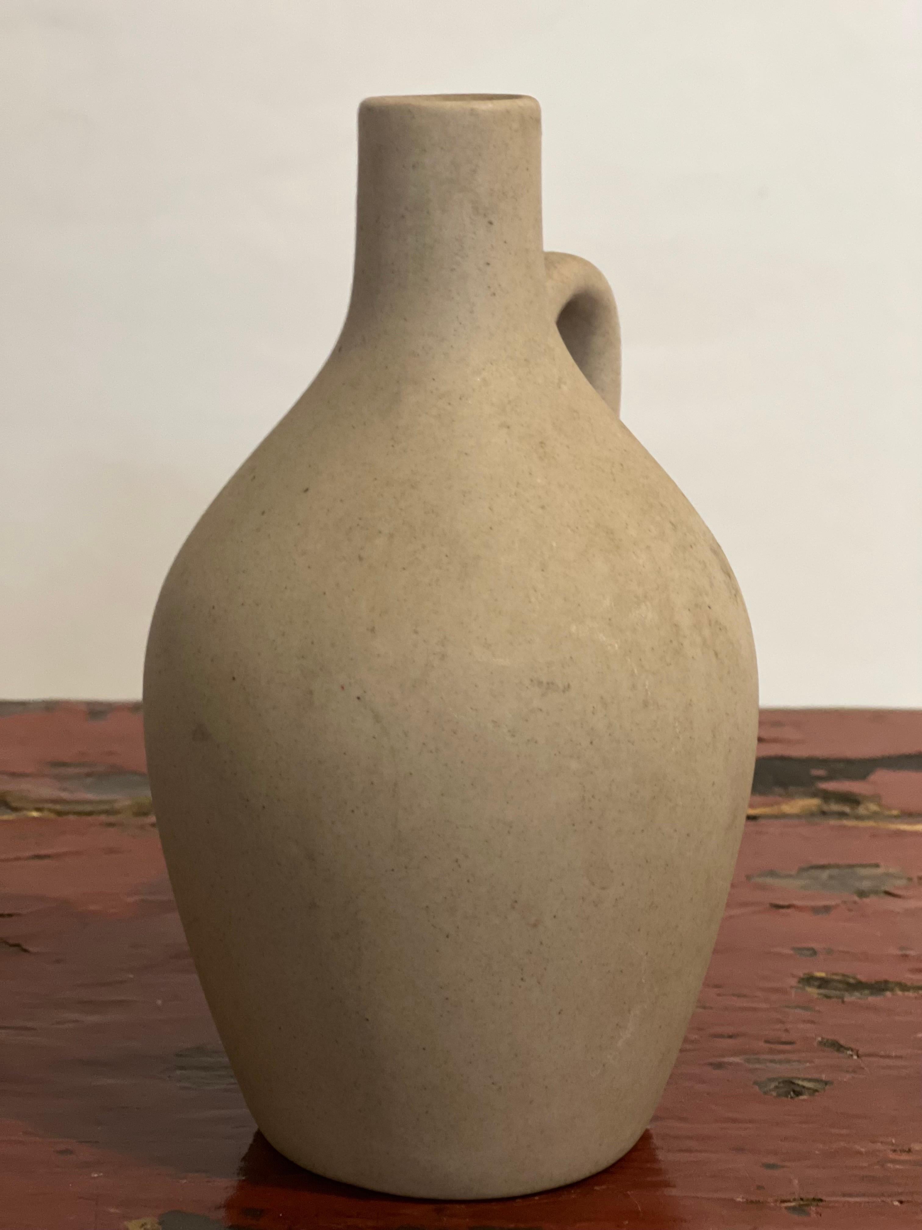 Mid-20th century small stoneware jug by Pigeon Forge Pottery, Tennessee.

Signed on the bottom, this adorable, matte beige jug has been handcrafted and individually fired. Perfect as a bud vase with a minimalist single flower or small arrangement.