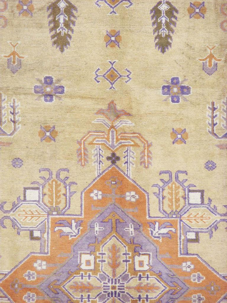 A vintage Turkish Oushak carpet from the mid-20th century. This unusual western Turkish Oushak is delineated in the Persian Heriz manner with a stepped soft orange pendant medallion on a camel-beige ground accented with floating vegetal motives