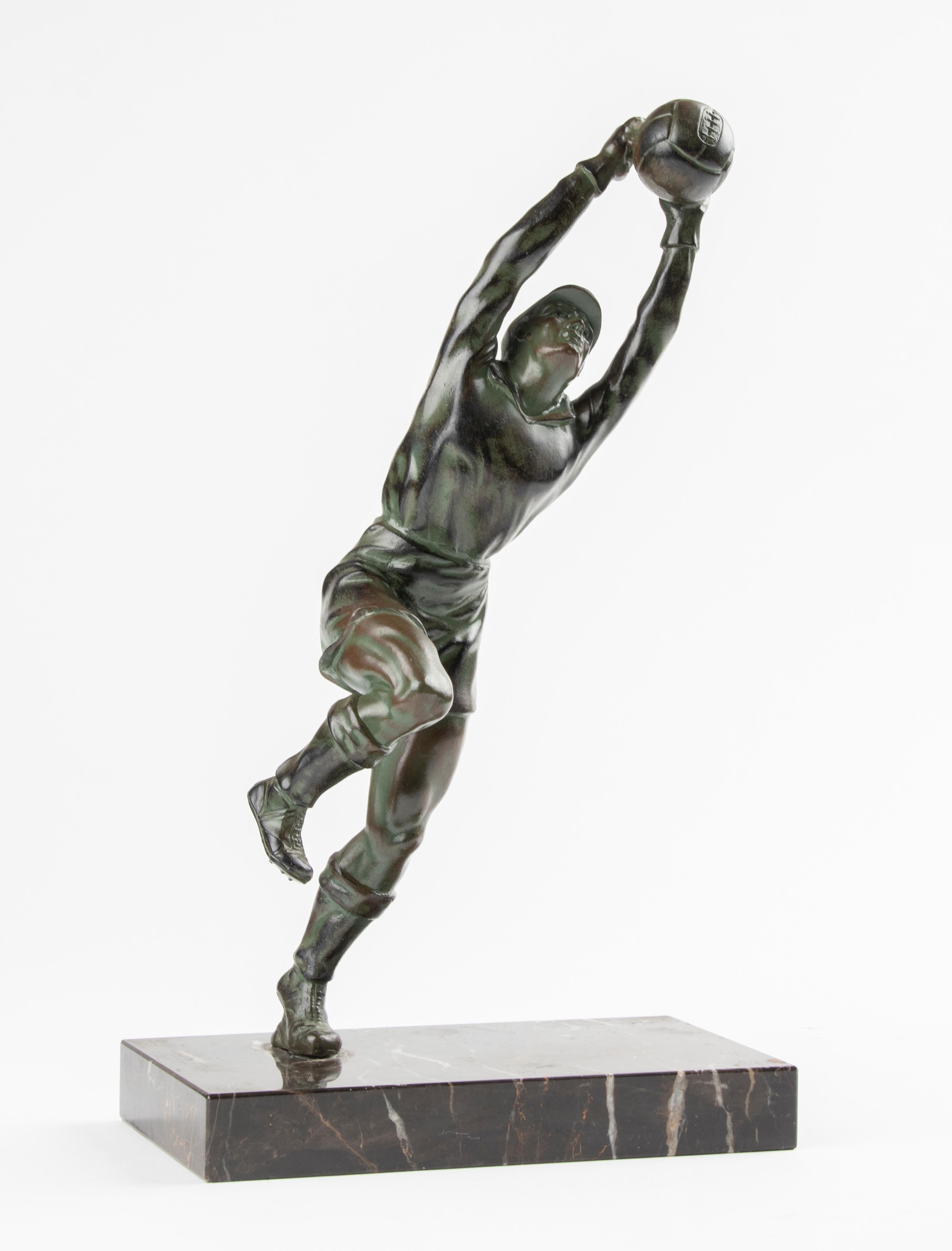 An Art Deco style sculpture of a football goalkeeper. The sculpture is made of cast spelter (zinc alloy), with a green patina. Standing on a marble plinth. Made in Belgium, circa 1950-1960.