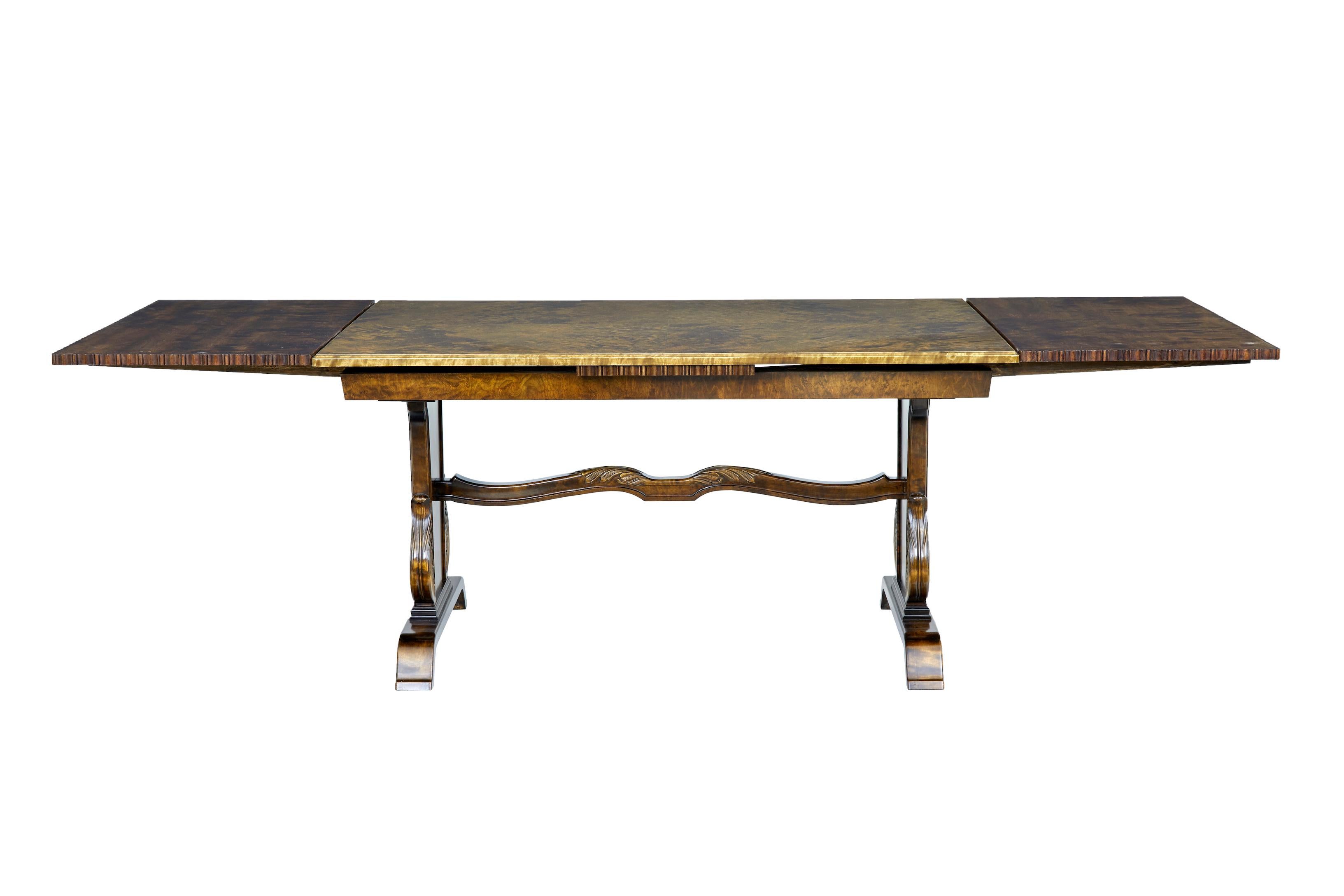 Fine quality late Art Deco carved birch dining table, circa 1940.

Made by Swedish company Bodafors smf.

Quarter veneered burr birch top surface with a draw leaf on each end, allowing it to seat upto 10 people. Standing on a tapering base with