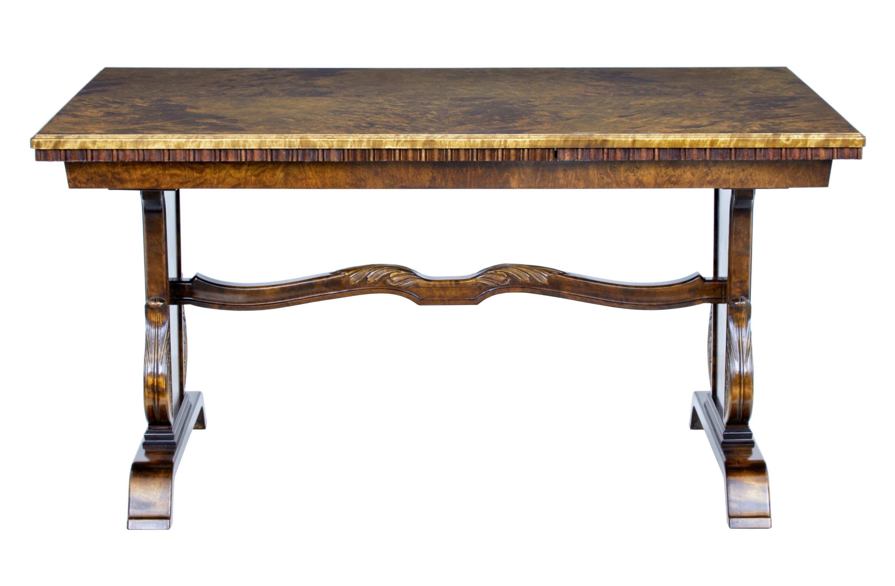 Fine quality late Art Deco carved birch dining table, circa 1940.

Made by Swedish company Bodafors SMF.

Quarter veneered burr birch top surface with a draw leaf on each end, allowing it to seat up to 10 people. Standing on a tapering base with