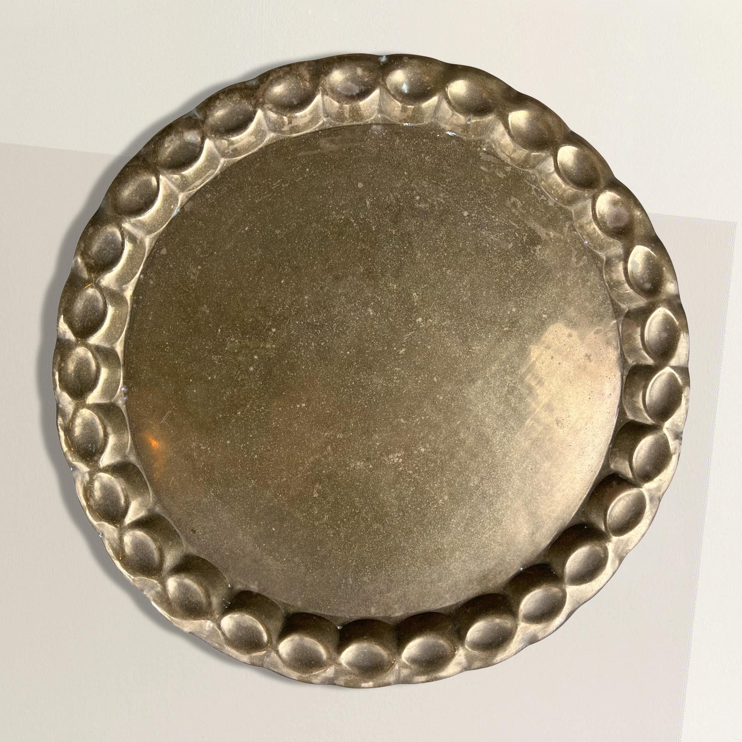 A wonderful mid-20th century Swedish hand hammered brass tray with a large dimpled rim. Perfect for serving myriad foods or drinks at your next cocktail party, but also easily at home on your coffee table and used to store books, remotes, or candles.