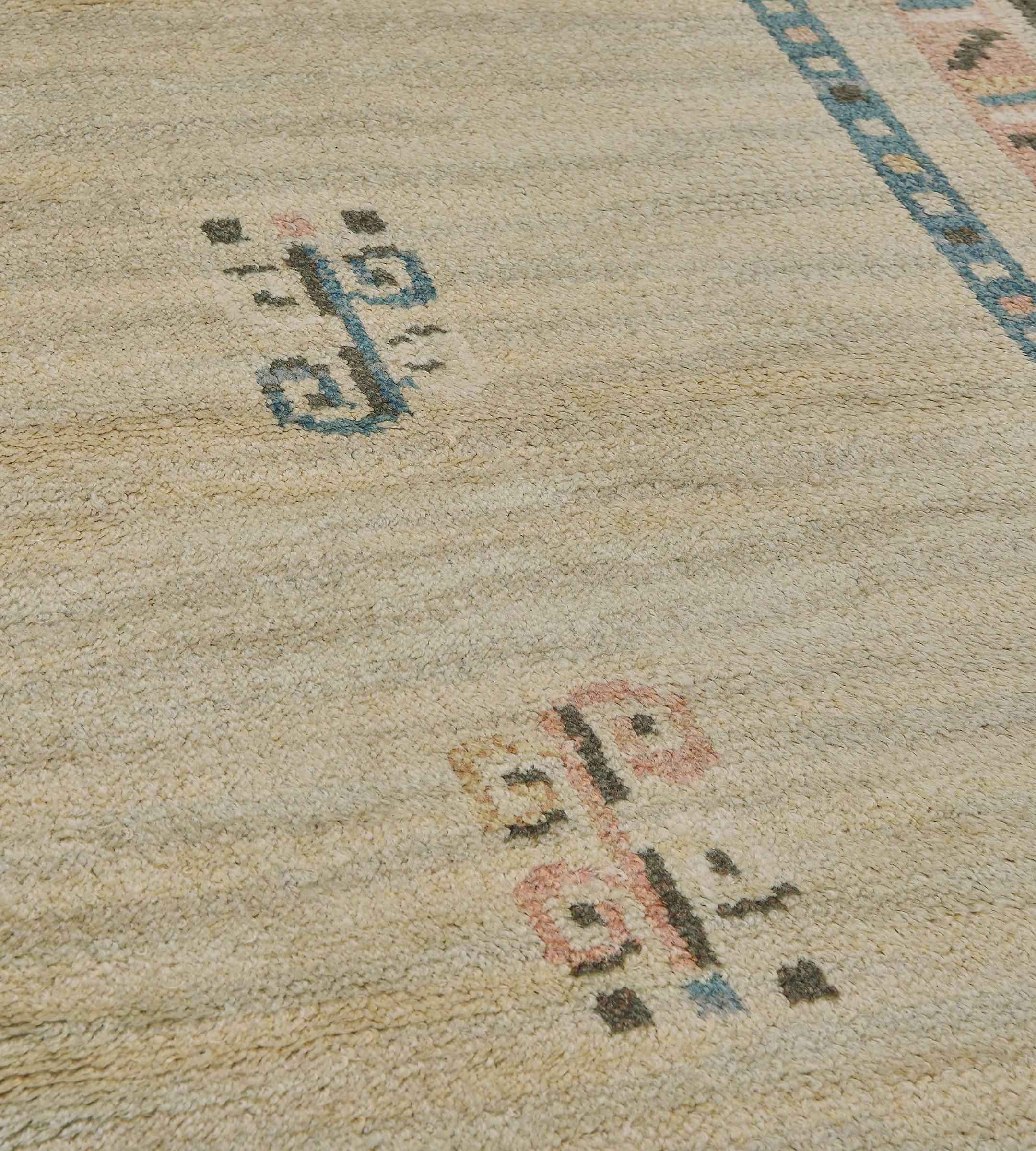 Ce tapis déco suédois d'époque, tissé à la main, présente un champ ouvert de couleur ivoire avec de délicats motifs de tiges bouclées, ainsi que deux élégants panneaux opposés de couleur bleu marine avec des motifs similaires, dans une bordure