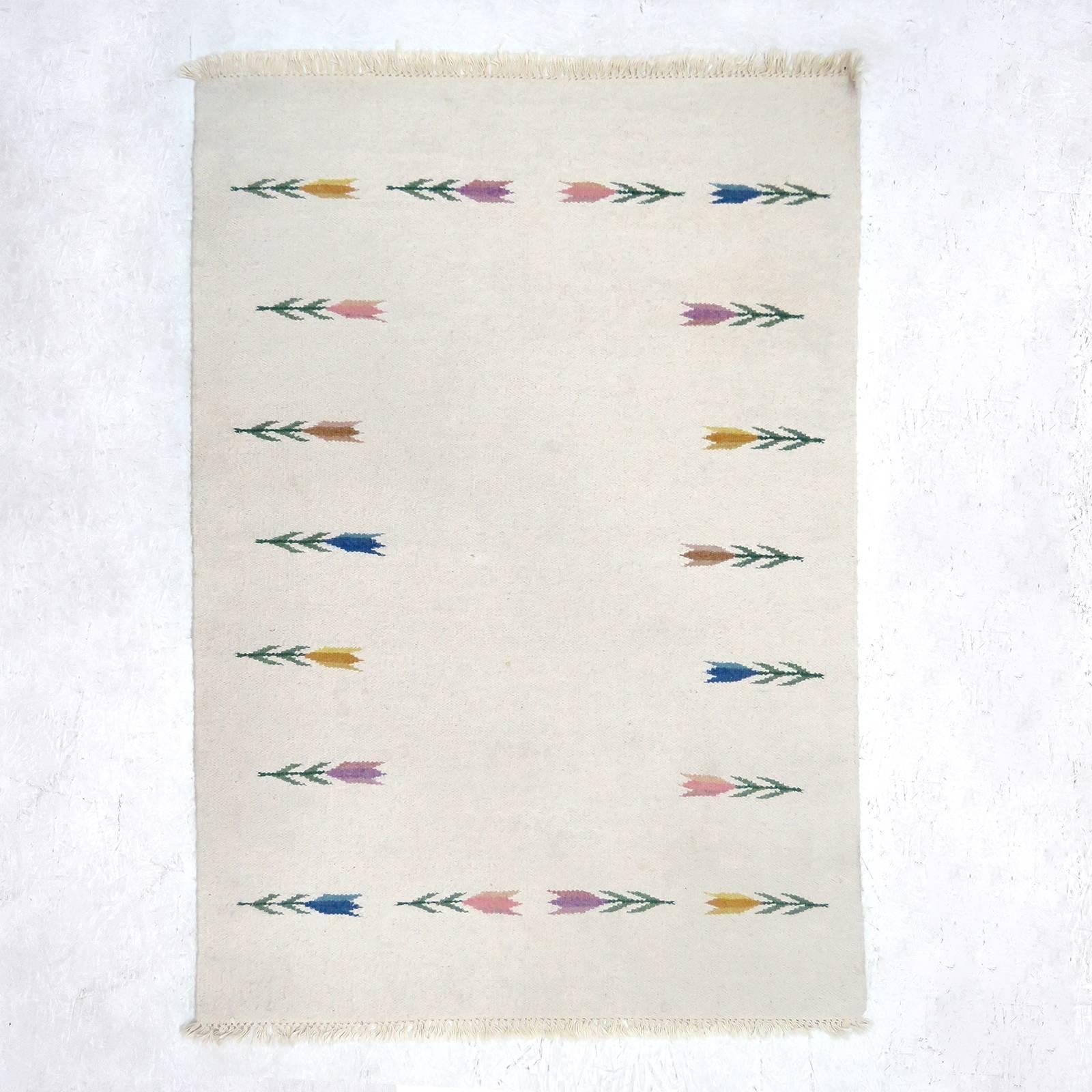 Magnifique tapis beige clair tissé à plat avec un motif de fleurs stylisées colorées.
