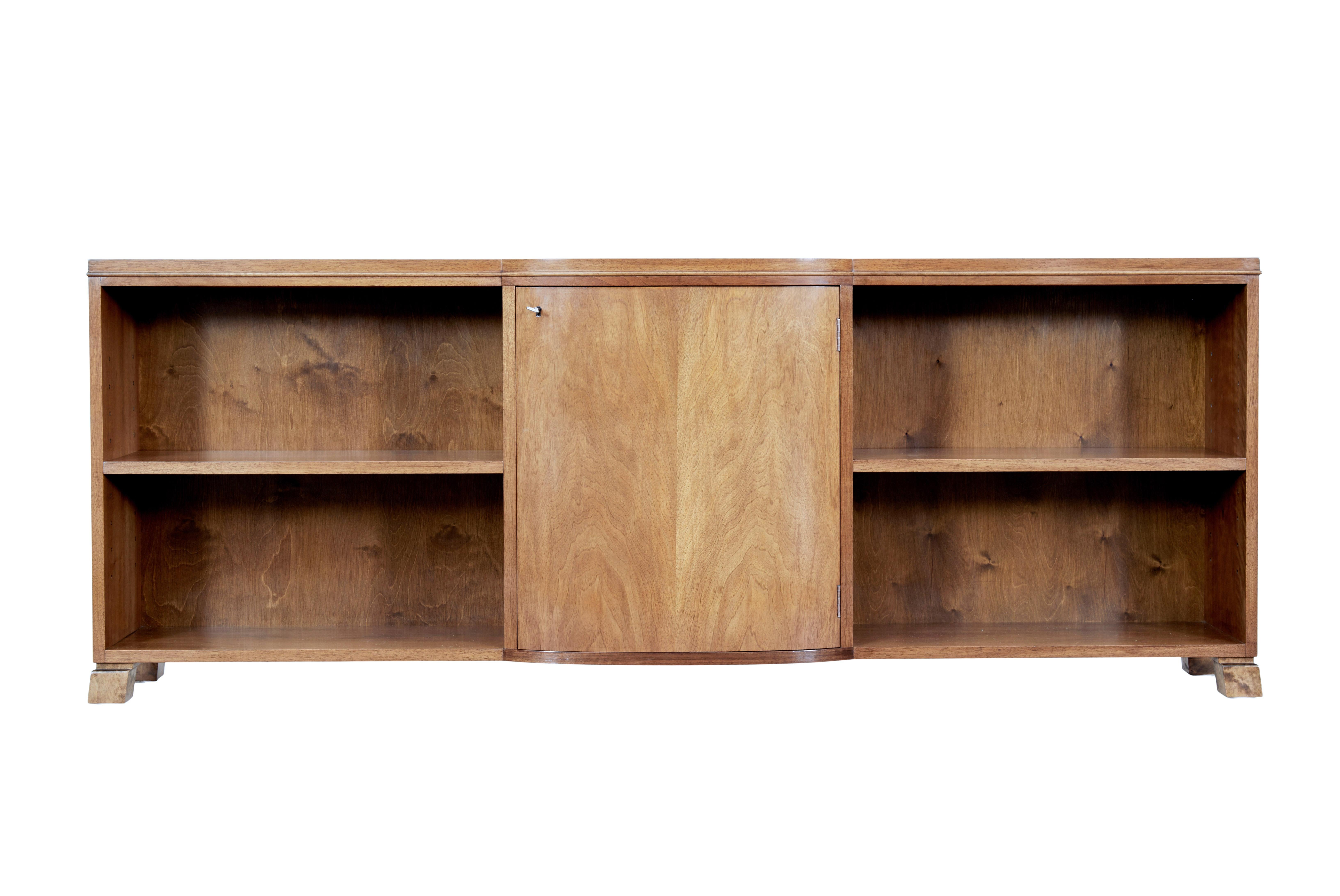 Mid-20th century Swedish low open bookcase in walnut circa 1950.

Fine quality piece of furniture made in Sweden which is unusually made in walnut. Bow front central single door cupboard containing a single adjustable shelf, flanked either side by