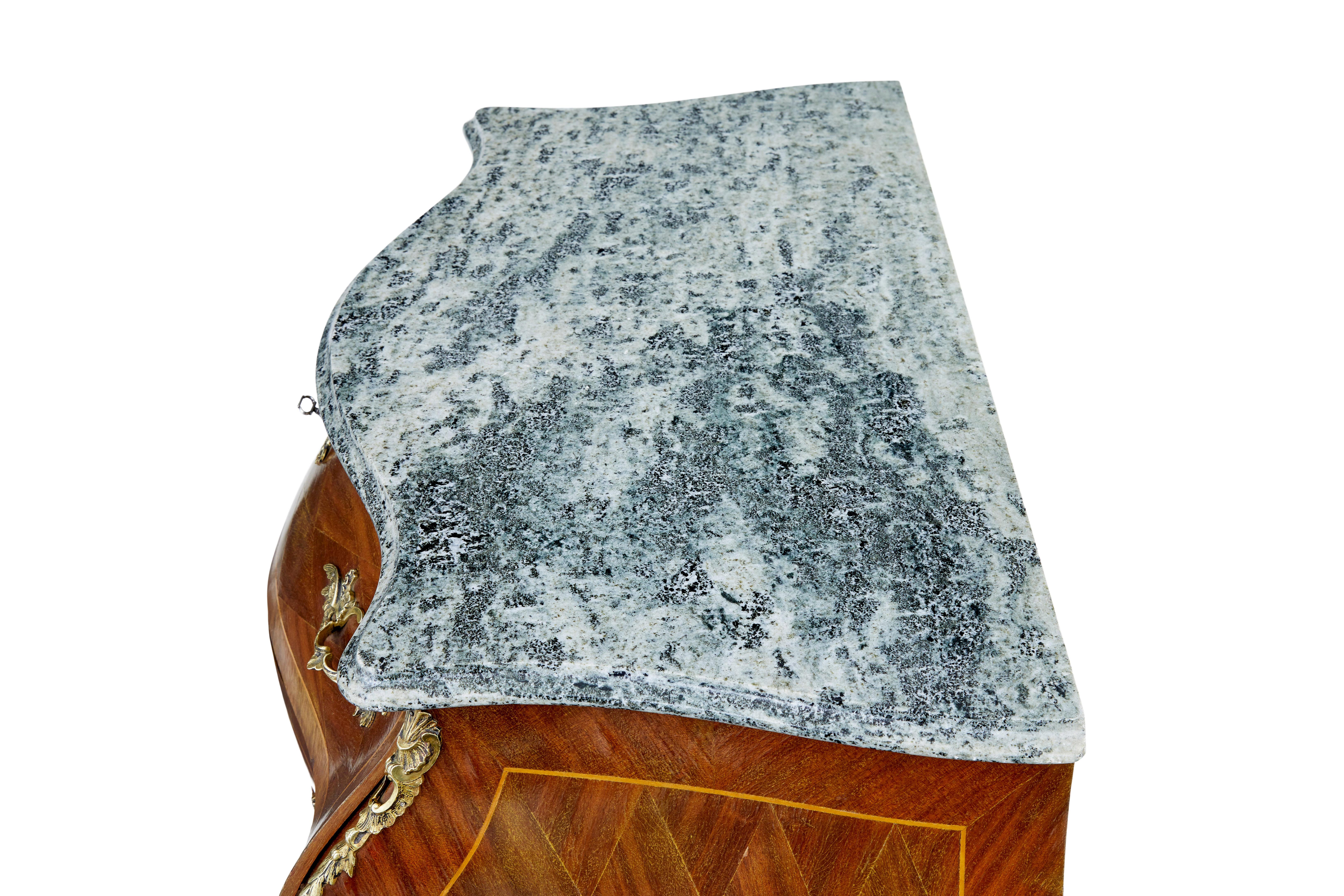 Mid 20th century rococo revival commode circa 1950.

Bombe shaped 3 drawer commode made in mahogany and kingwood, with shaped marble top. Green and grey marble is loose fitting for easier movement and shipping.

Arranged mahogany veneers with
