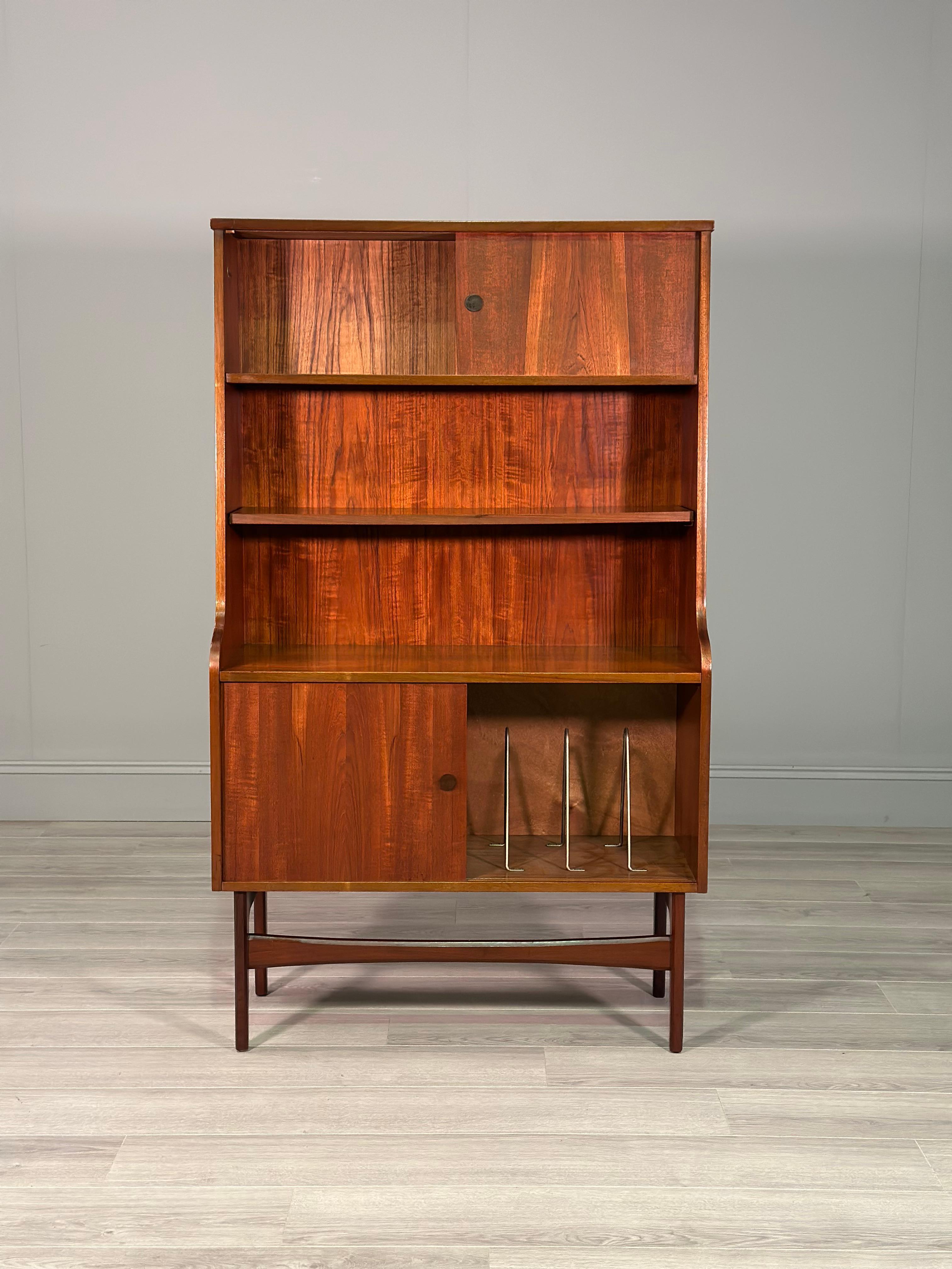 A small in size teak highboard cabinet dating to the 1960’s. The cabinet has a Danish feel and still retains it’s original British retailers mark. It consists of two sliding door cupboards a small one to the top and a large one to the bottom still