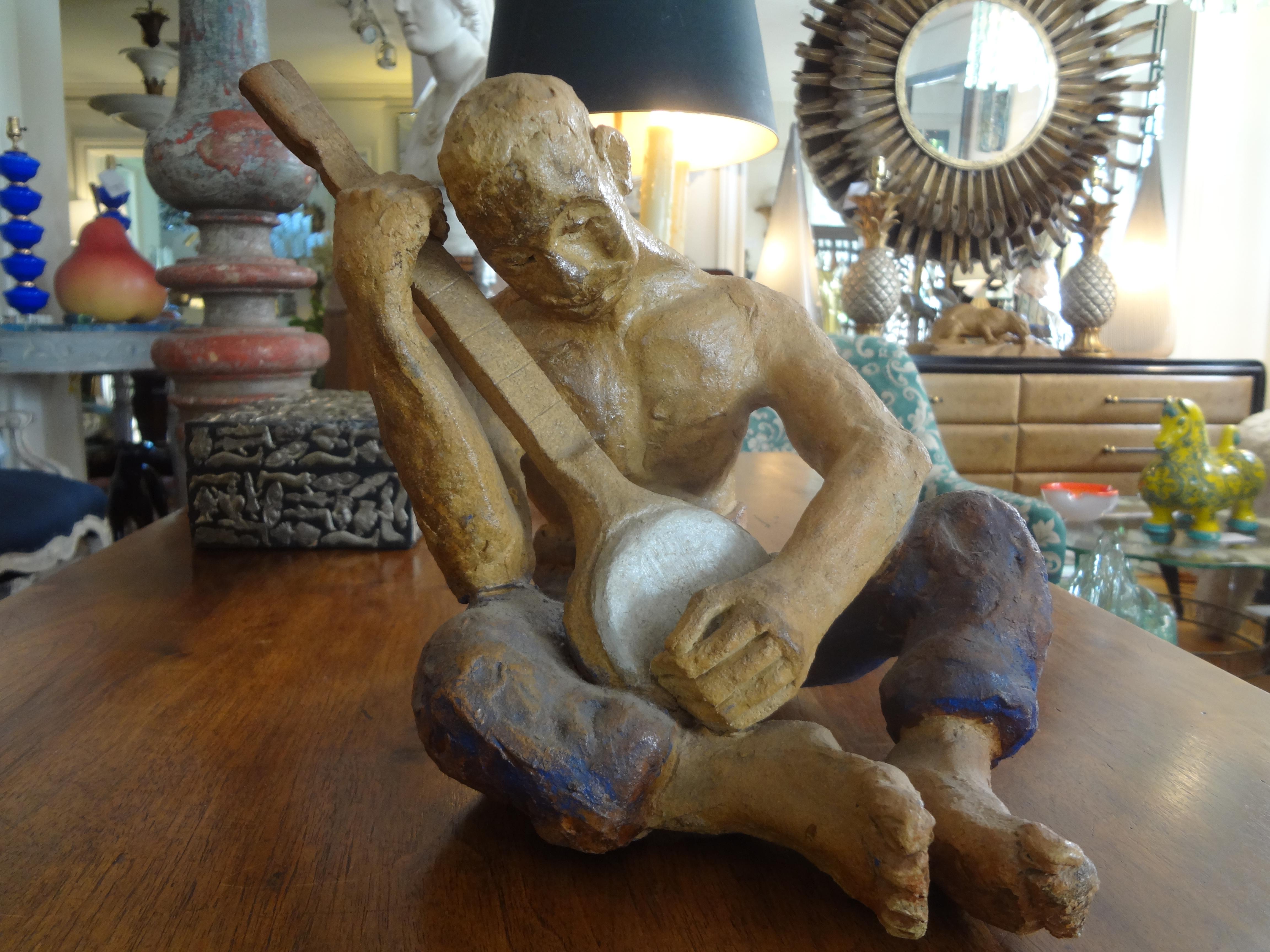Mid-20th Century terracotta or clay figural sculpture. This vintage terra cotta sculpture depicts a man seated playing a musical instrument.