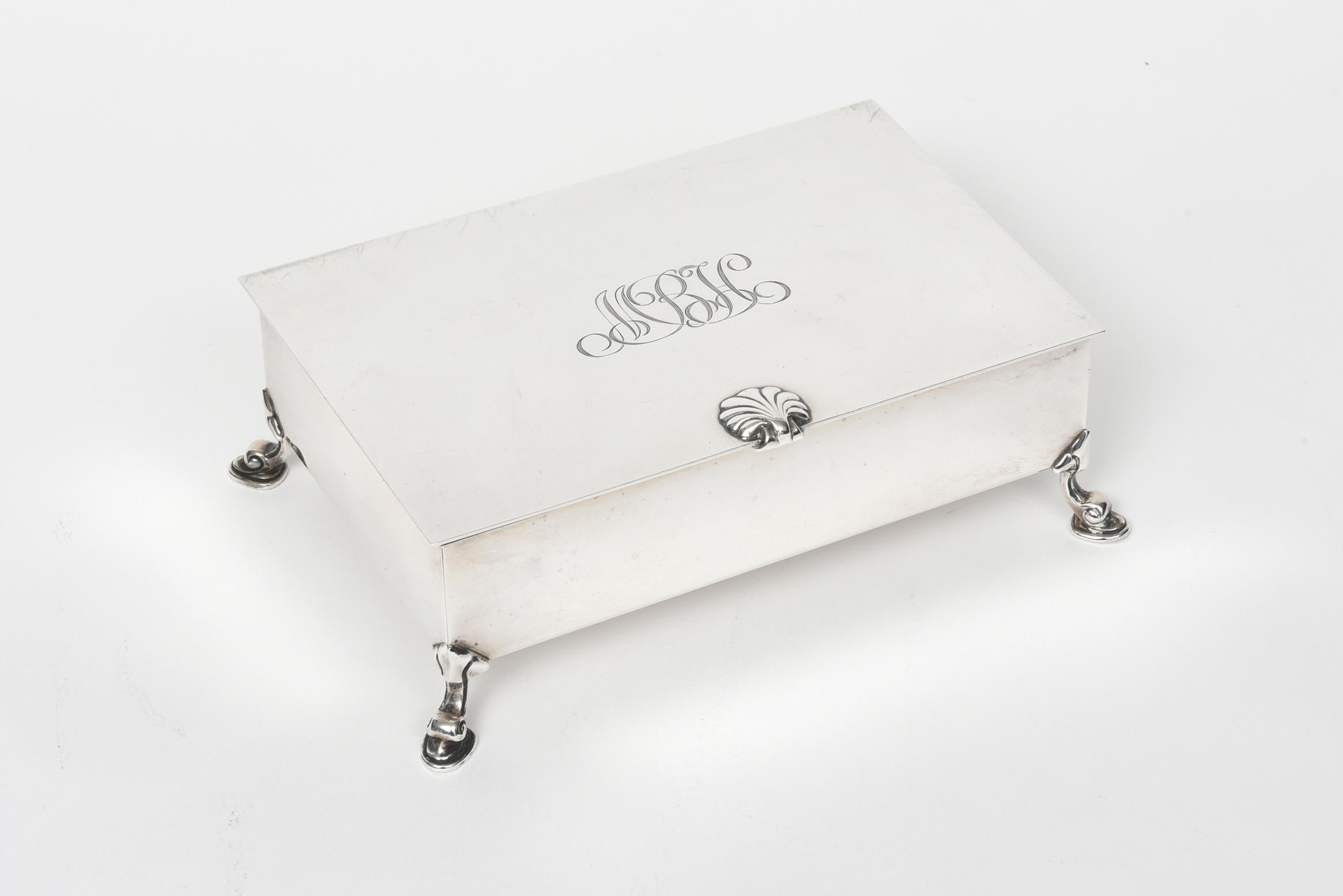 Tiffany & Co. rectangular sterling silver cigarette box rests on four inverted cabriole feet. Top of the box features a seashell detail handle and is initialed 