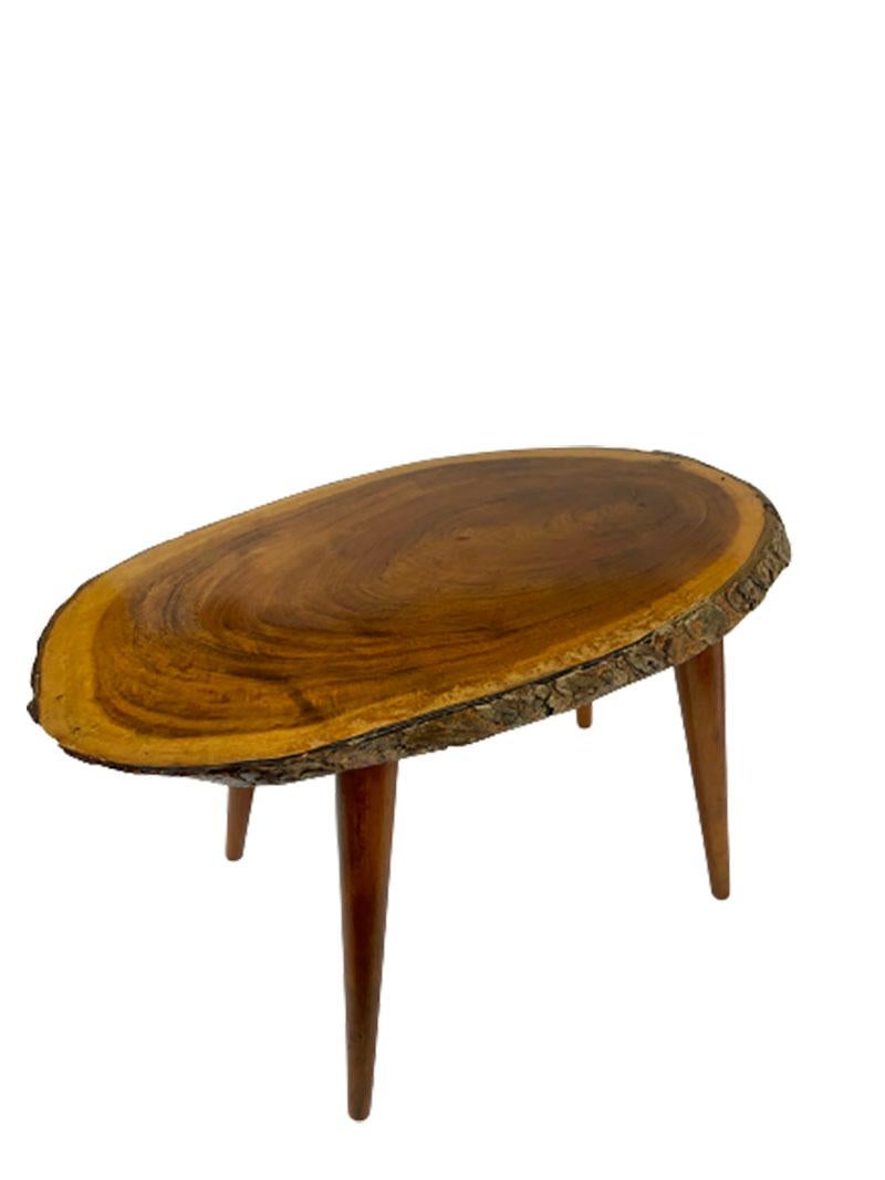 Mid-20th century tree trunk wine or side table 

A slice of a tree with bark with teak legs. The table is from the mid-20th century and in the style of the Viennese artist and designer Carl Auböck. It is a very nice table, but has light traces of