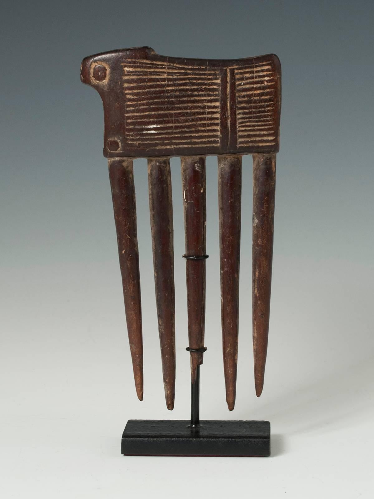 Offered by Zena Kruzick
Mid-20th century tribal African wood comb from the Baule, Cote d'Ivoire

 A charming comb in the shape of a large beast of burden comes mounted on a custom stand.