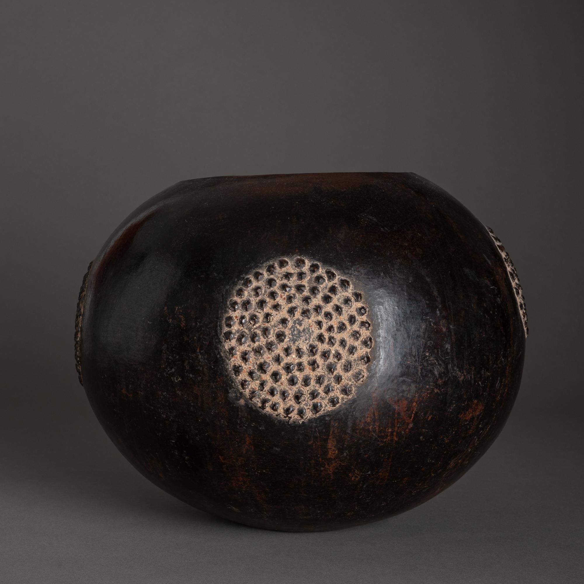 Zulu beer pots, or Ukhamba, are shaped with the coil method, then smoothed, incised, indented or embossed with geometric patterns, and finally fired, which hardens the clay and darkens its surface. The black, glossy finish of this Ukhamba,