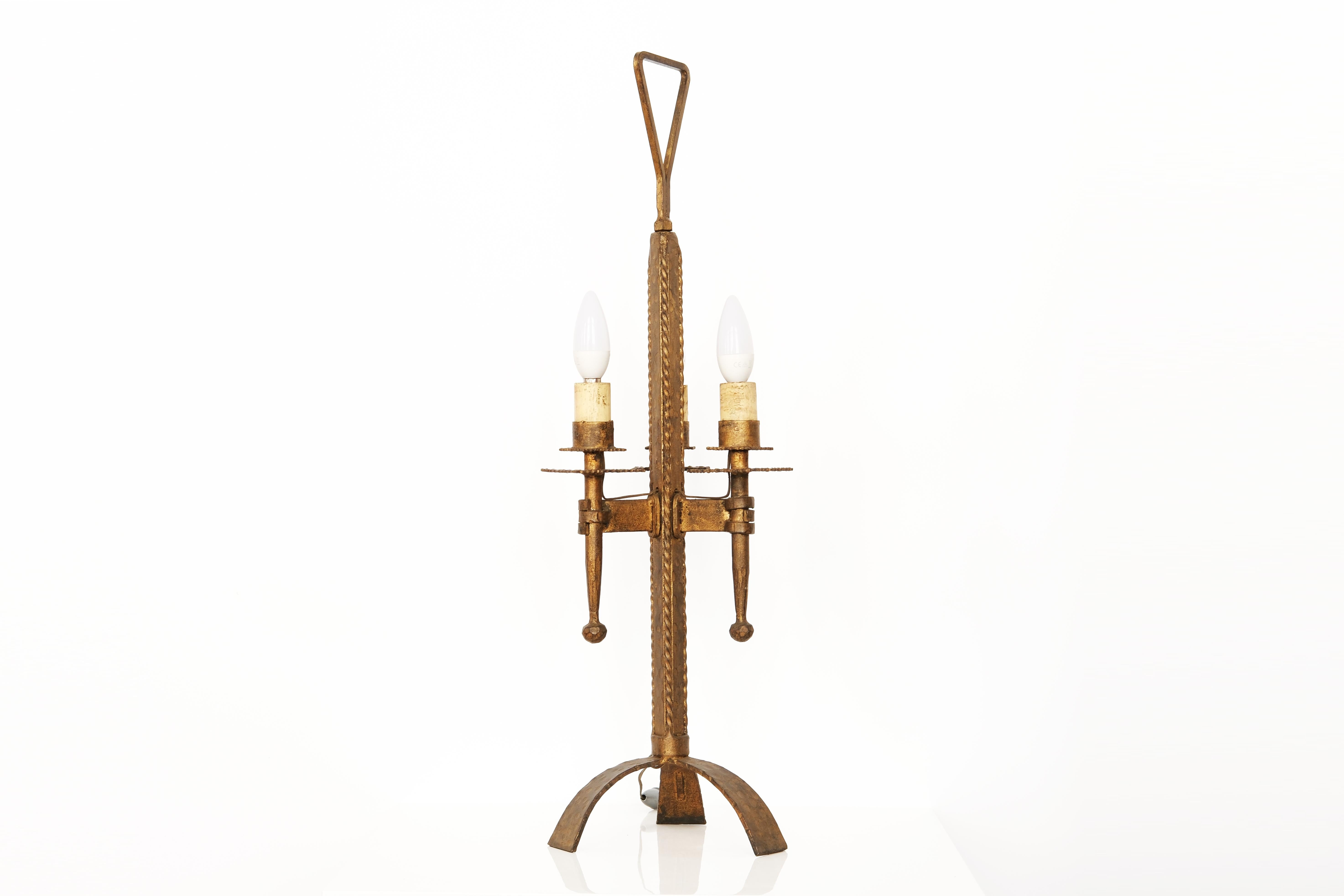 Cette lampe de table remarquable est fabriquée en fer forgé doré, un bel exemple de l'artisanat espagnol du milieu du XXe siècle. Signé Ferro Art sur la base, il présente les détails martelés à la main caractéristiques de la marque et un design