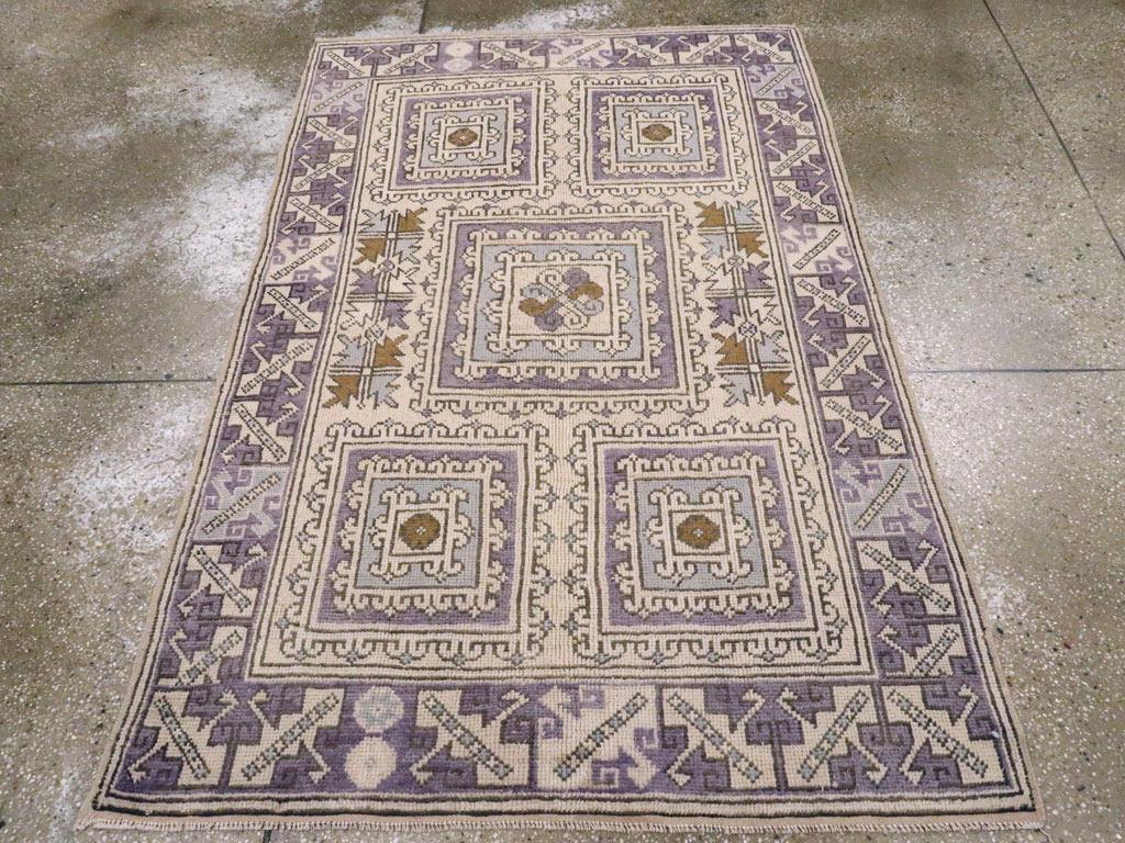 A vintage Turkish Anatolian throw rug. This pale straw ground scatter has a 2/1/2 pattern of hooked, nested square medallions characteristic of villages in the Bergama district of NW Anatolia. The royal blue border has stepped, slanted leaves in