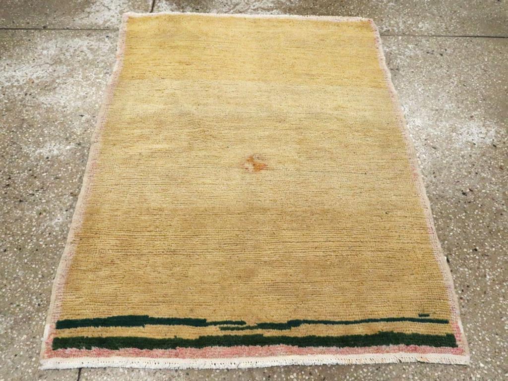 Ein türkisch-anatolischer Teppich im Vintage-Stil. Zarte, strohfarbene Paneele flankieren horizontal einen breiten Abschnitt aus altem Elfenbein mit einem winzigen zentralen Kreuzmotiv. Unregelmäßige dunkelbraune Wolken ziehen über das obere Ende.
