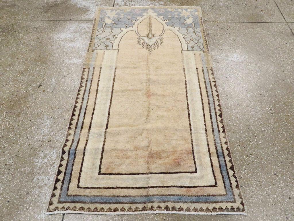Ein türkisch-anatolischer Teppich im Vintage-Stil. Ein schlichtes, warmbeiges Nischenfeld wird von einer Reihe einfarbiger Bänder flankiert und eingefasst. Die linearen Ranken- und Palmettenzwickel gehen vom Himmel ins Hellblau über. Eine