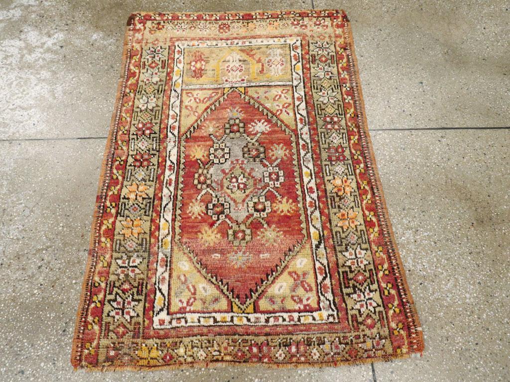 Ein türkisch-anatolischer Teppich im Vintage-Stil. Ein abgewetztes rotes Feld wird von einer Rosette und einem Nelkenrautenmedaillon nahezu ausgefüllt. Oberhalb des Feldes befindet sich eine Tafel mit einem spitzen Wolkenbandmuster. Das