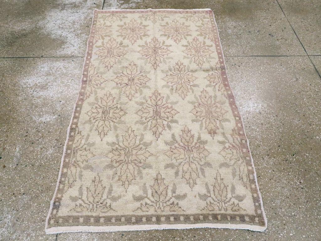 Ein türkisch-anatolischer Teppich im Vintage-Stil. Eine schmale Bordüre mit taupe- und beigefarbenem Punktmuster umrahmt das Austernfeld dieses anatolischen Dorfstreus mit seinen halbtropfigen Reihen aus vier Vierblüten. Dieses Design ist eindeutig