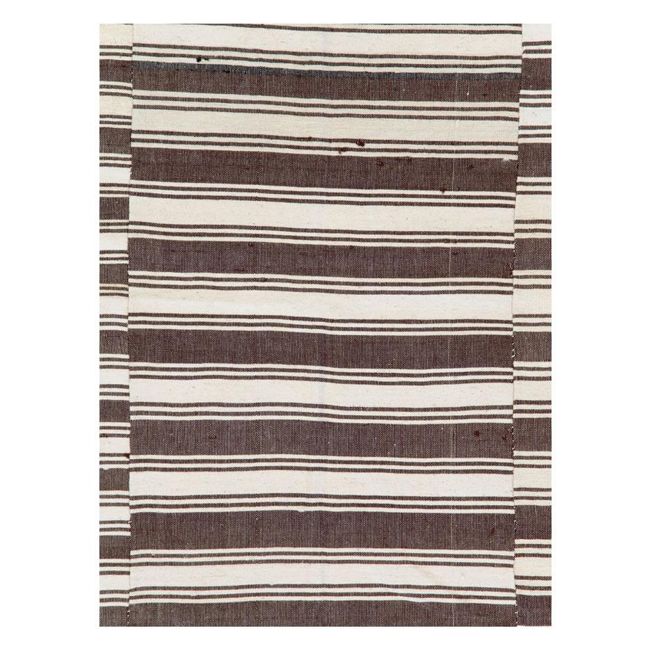 Un tapis d'accentuation Kilim turc vintage à tissage plat, fabriqué à la main au milieu du 20e siècle, avec un motif décalé à rayures horizontales dans des tons de brun, crème et noir.

Mesures : 6' 2