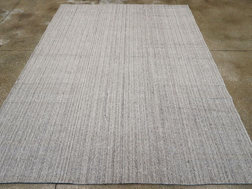 Esta alfombra kilim turca de tejido plano de mediados del siglo XX, que mide 2,8 m x 2,8 m, presenta un sutil diseño de rayas verticales en una suave paleta de grises apagados. La delicada textura y las variaciones tonales de la superficie resaltan