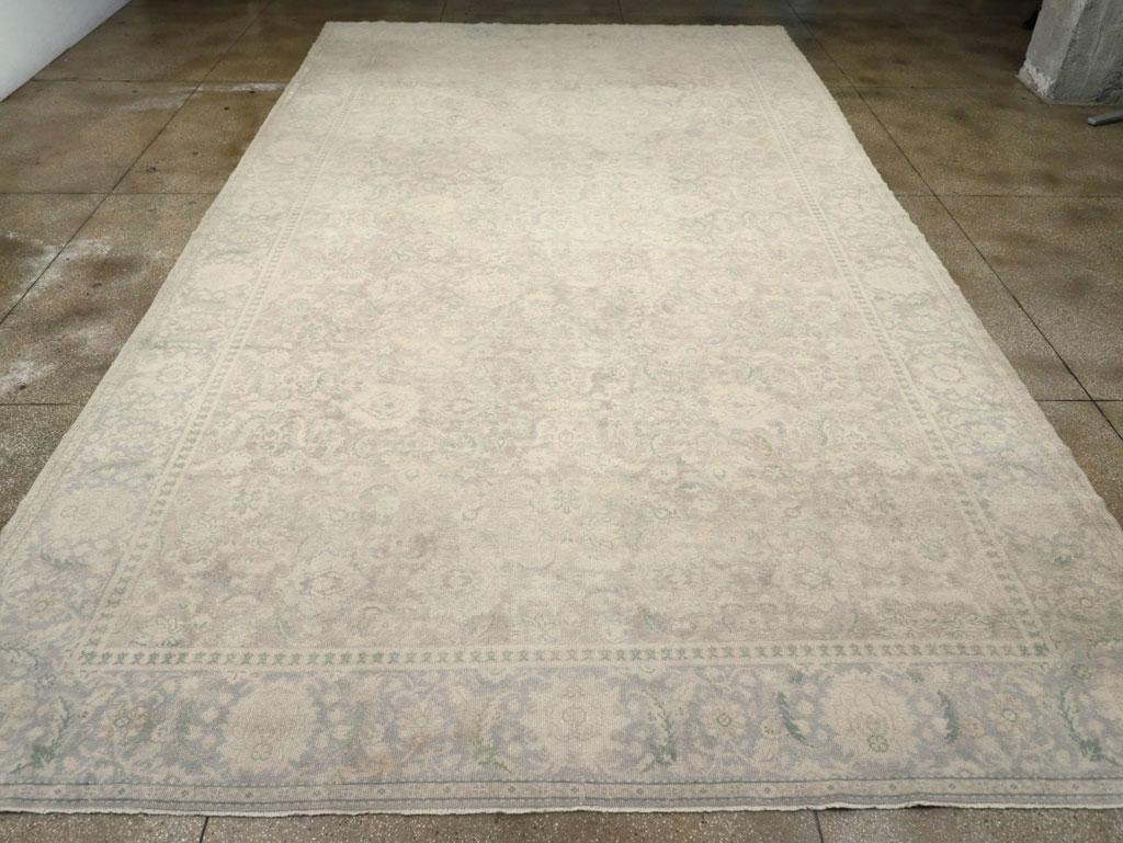 A wool pile of symmetric knots on a cotton foundation. With a significantly reduced palette, the light brown field hosts an all-over, repeating design of palmettes and leaves in a Persian style. Generally in the Interwar Oushak manner. Pale