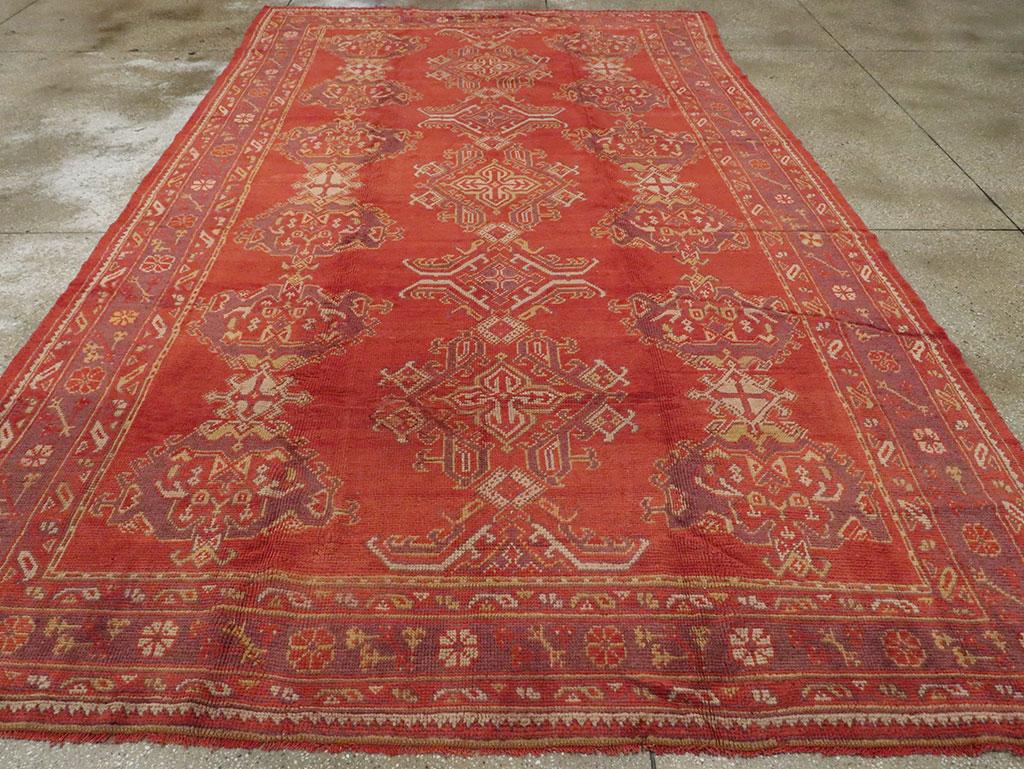 A Vintage Turkish Oushak room size carpet. Similar generally to our rug # 8815, but here the field order is reversed with a central column of lozenges, cruciforms, and bent leaf brackets, flanked by two columns of conjoined complex Harshang