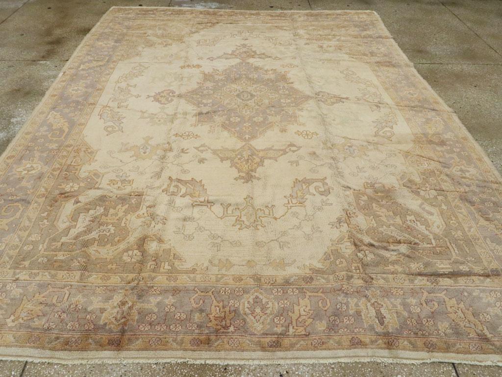 A vintage Turkish Oushak room size carpet. The pearl ground of this Turkish room size carpet displays sawtooth, curved leaves and small floating turtle palmettes around a light blue lozenge medallion with escutcheon pendants. Light blue is picked up