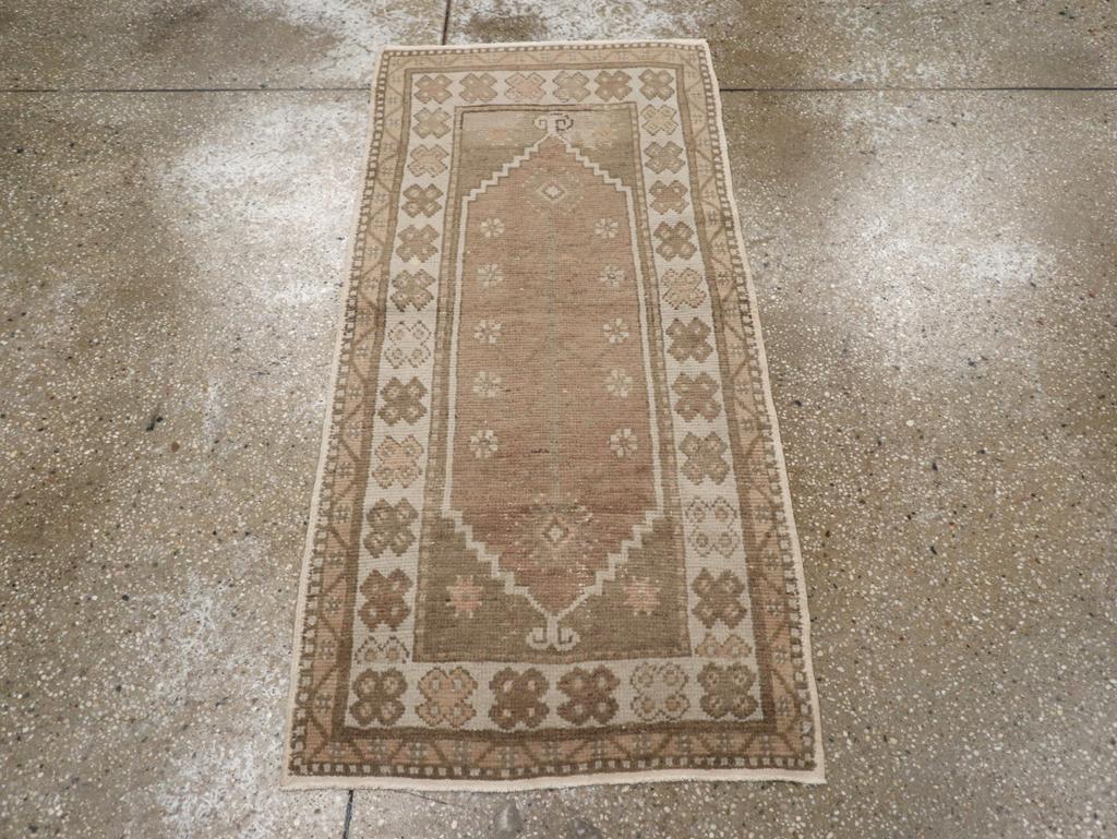 Ein alter türkischer Oushak-Teppich. Dieses schmale, rustikale Streugut hat ein mittelbraunes Feld mit einer spärlichen Dekoration aus einem zentralen dünnen Stiel und baumelnden Rosetten. Das breite elfenbeinfarbene Hauptband ist mit fetten
