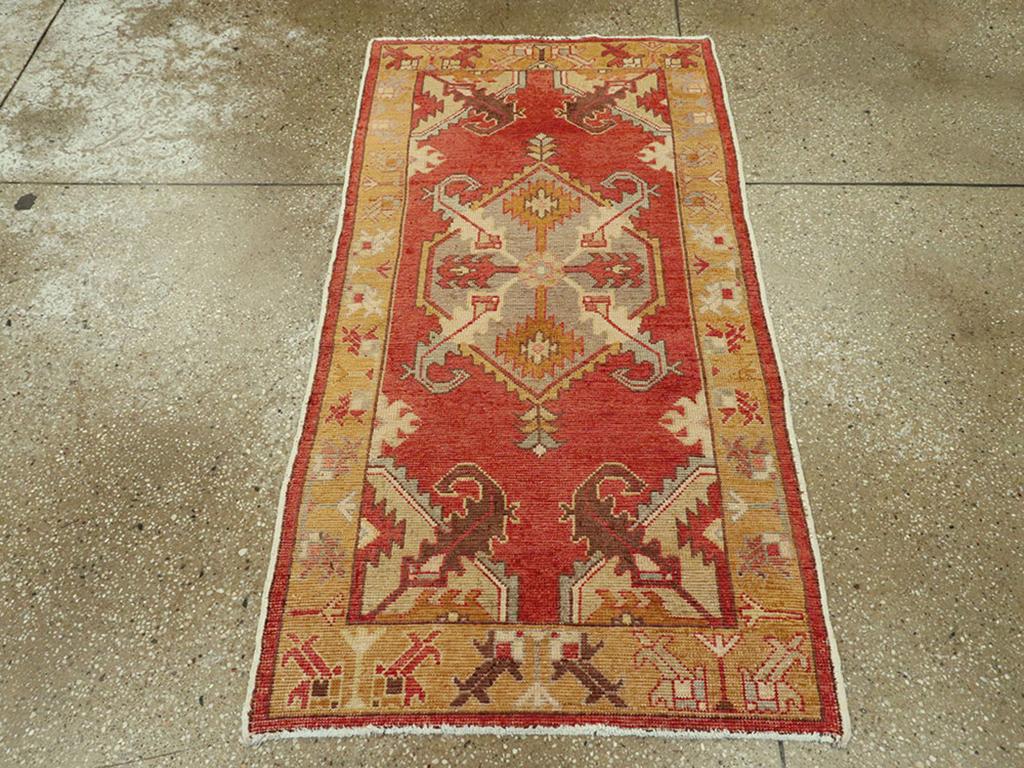 Un tappeto Oushak turco vintage. Un medaglione esagonale color malva dal bordo seghettato fa spuntare quattro grandi e aggressive foglie diagonali che si abbinano a quelle emanate dagli angoli dei quarti nel morbido campo rosso. Il bordo ocra