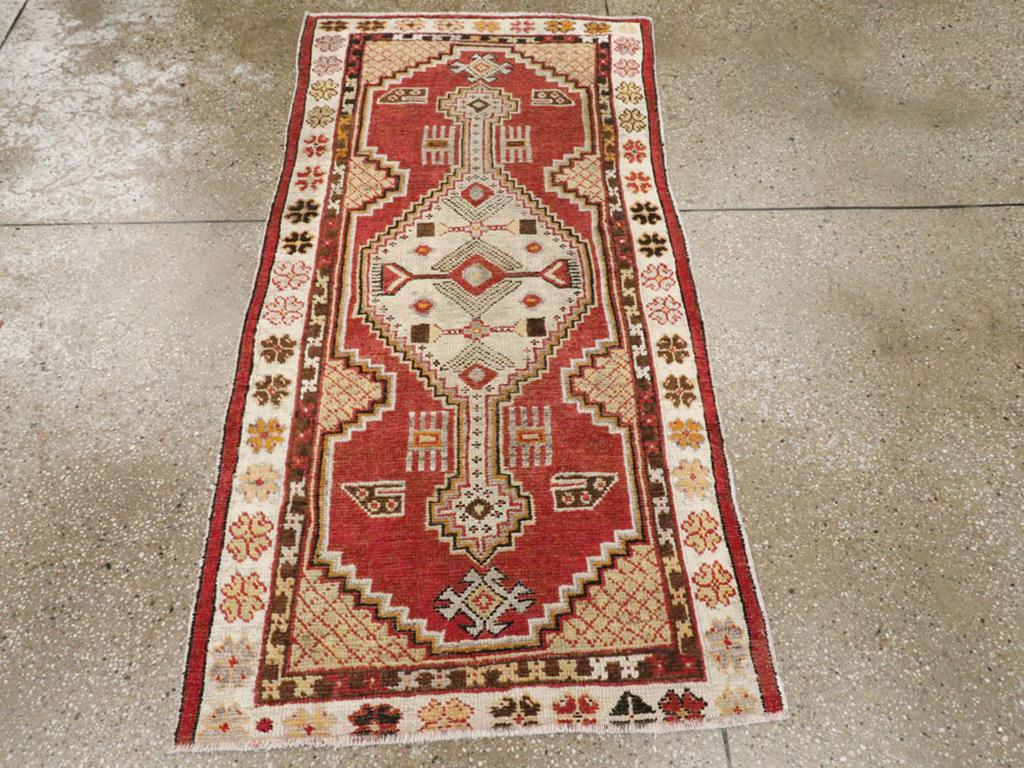 Ein alter türkischer Oushak-Teppich. Ein gestuftes, hängendes, geometrisches, längliches elfenbeinfarbenes Medaillon ist auf einem roten Unterfeld mit schwebenden Doppelkammvorrichtungen und senfgelben kreuzschraffierten Seiten- und Eckfülldreiecken