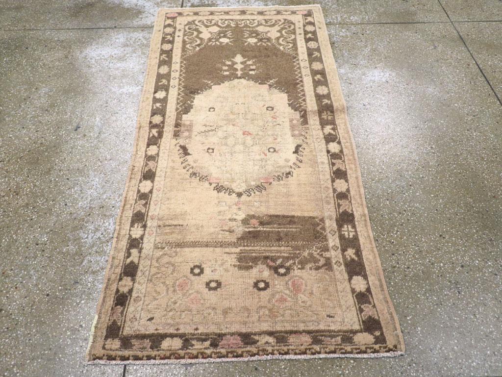 Un tappeto Oushak turco vintage. Il campo è fortemente abraso, da marrone medio-scuro a beige, in questo stretto spargimento dell'Anatolia occidentale con un medaglione centrale in avorio schiacciato e frangiato. La macchia di abrash marrone a metà