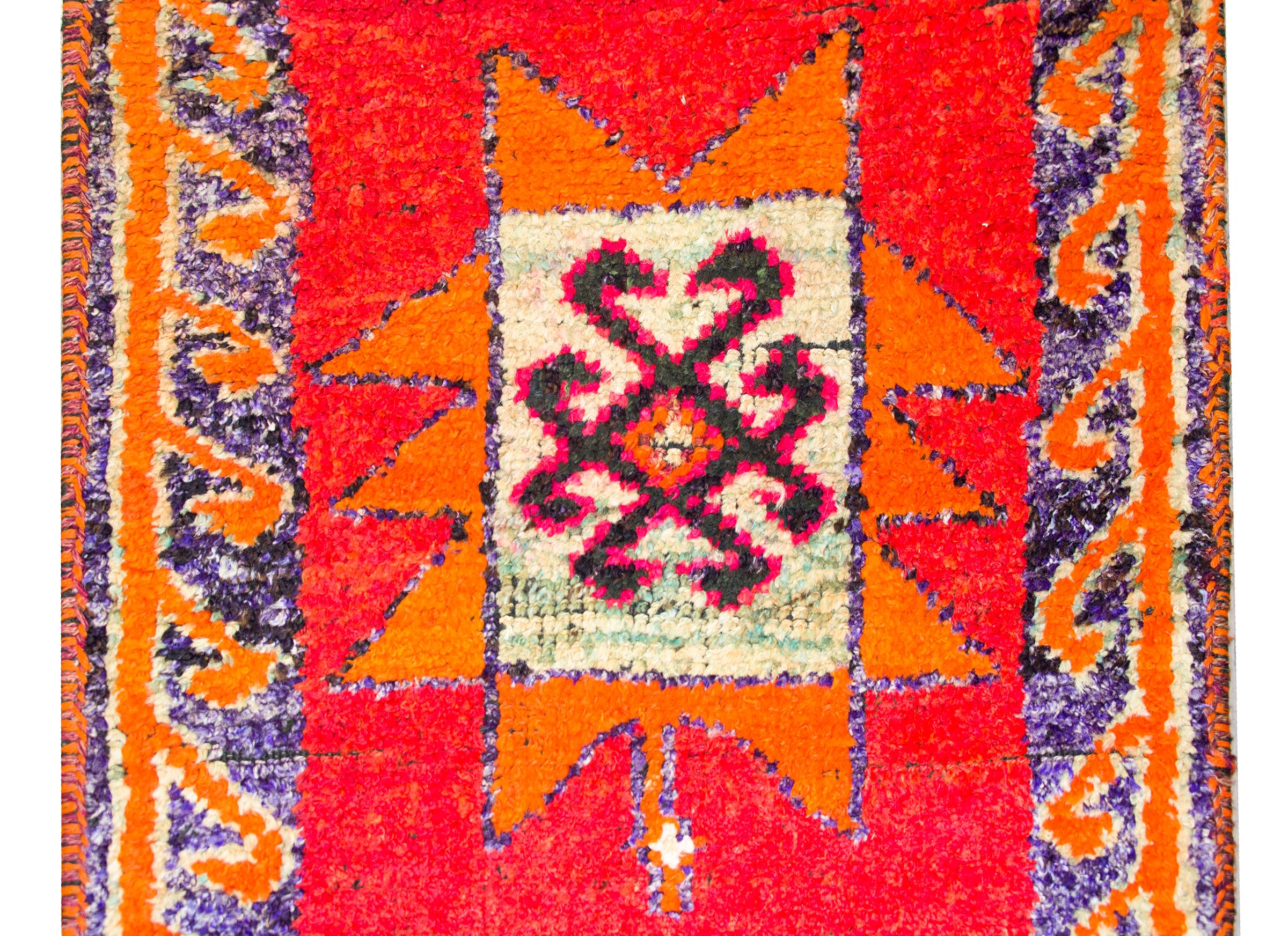 Ein kühner und brillanter türkischer Teppich aus der Mitte des 20. Jahrhunderts mit vier großen stilisierten Blumenmedaillons in leuchtenden Rosatönen, Grüntönen, Orangen, Veilchen und Fuchsien, die vor einem karminroten Hintergrund gewebt sind und