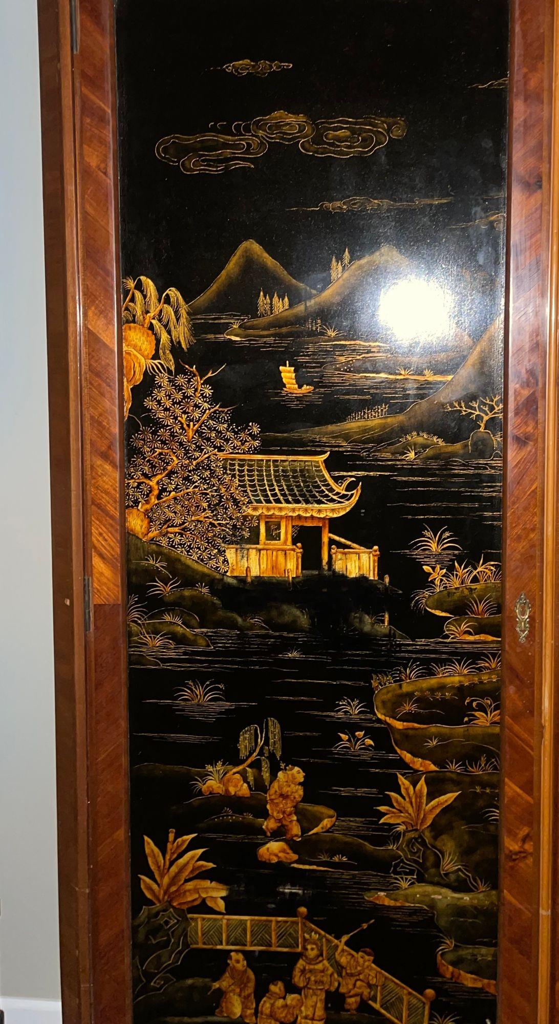 Llamativo armario francés de dos puertas de mediados del siglo XX, con paneles de laca chinoiserie exquisitamente pintados a mano. Las puertas presentan un elegante fondo de laca negra con figuras detalladas, pabellones, montañas y escenas