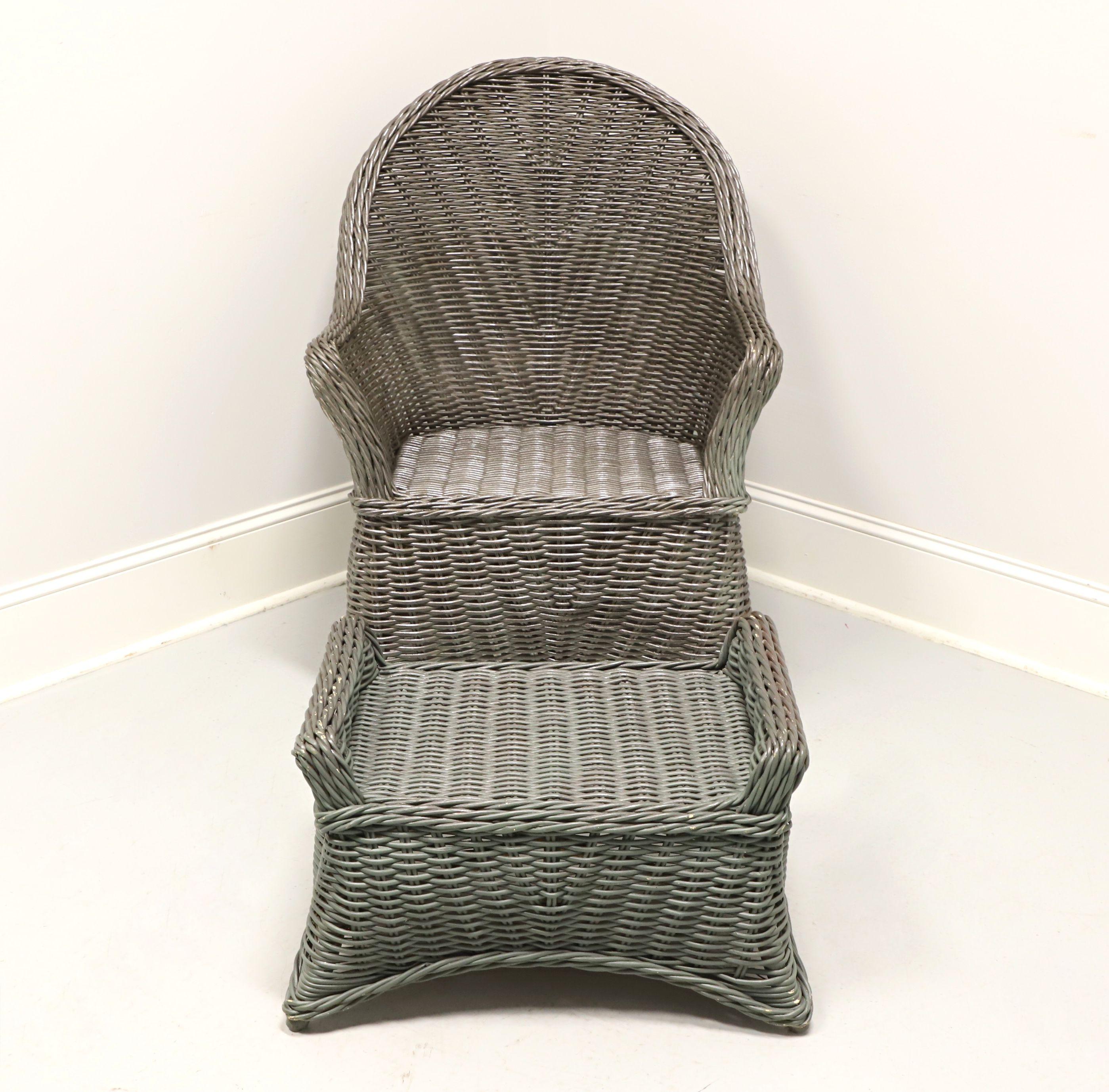 A Victorian style wicker armchair and ottoman, unbranded. Gray painted woven wicker reed and wood under frame. Chair features wicker wrapped frame, herringbone weave design, curved arms, woven apron and wrapped flared legs. Ottoman has a matching