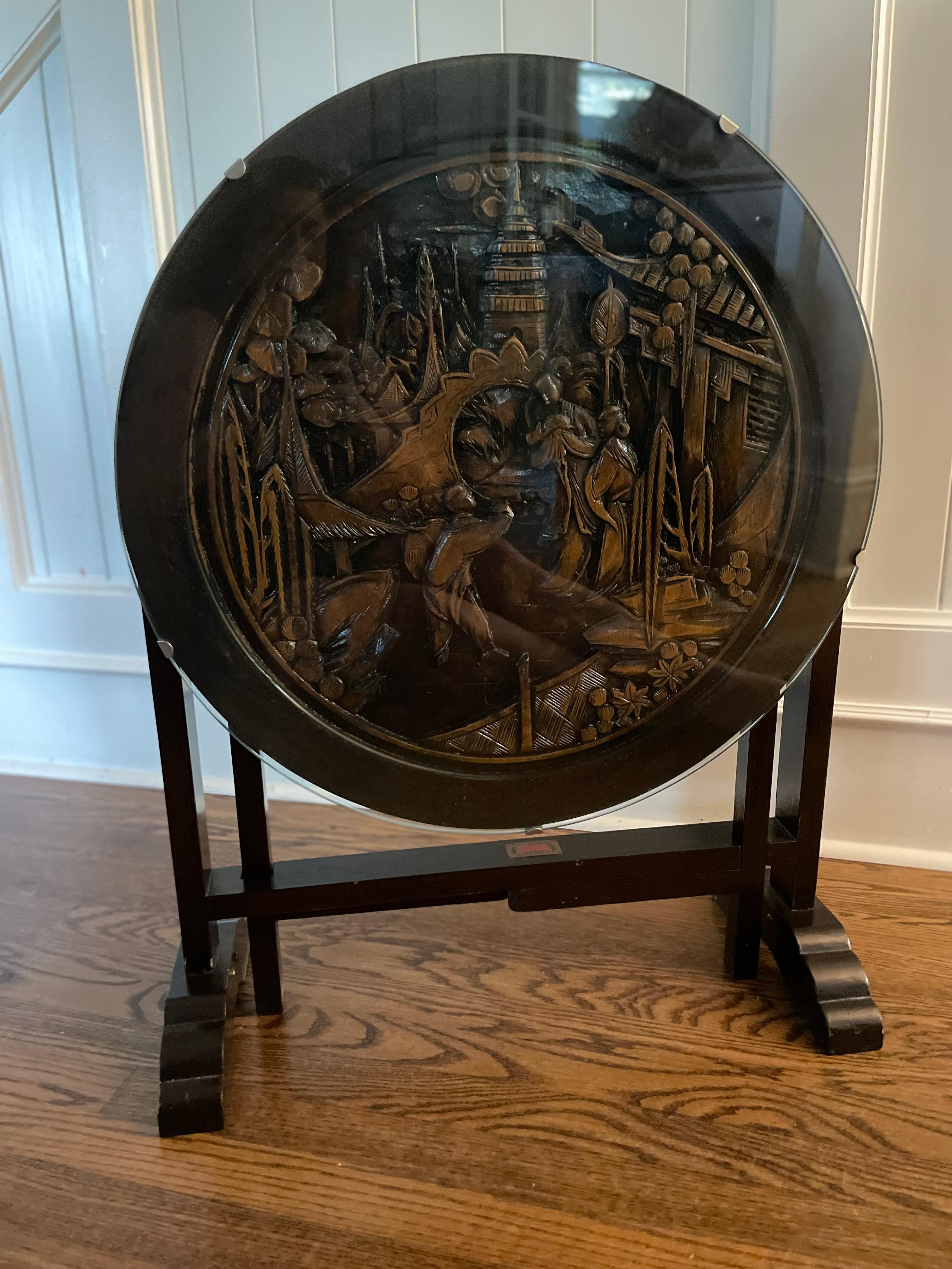Exquisitely hand-carved hardwood accent side tea table, early to mid 20th century. The circular tilt-top presents an exquisite, detailed relief sculpture with a Chinoiserie motif. Its graceful lines are raised on a trestle-style base and four gate