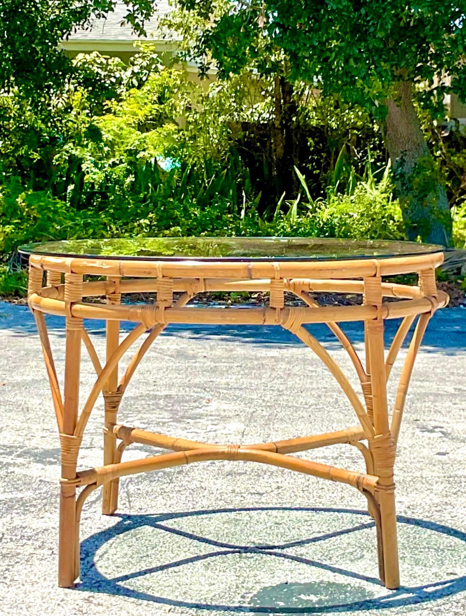 A fabulous vintage Coastal dining table. Beautiful bent rattan in a chic and simple design. Glass top. Acquired from a Palm Beach estate.