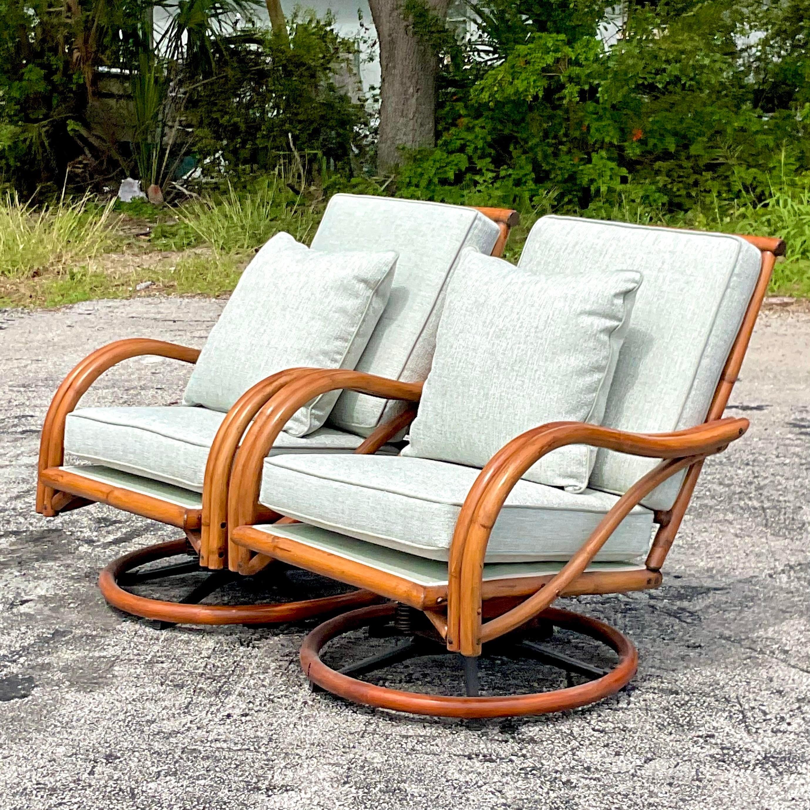 A stunning pair of vintage Coastal swivel chairs. Chic bent rattan with loop sides and a high back. Fully restored with a full rattan restoration and all new upholstery. A chic celadon Sunbrella fabric with the Krypton treatment for extra
