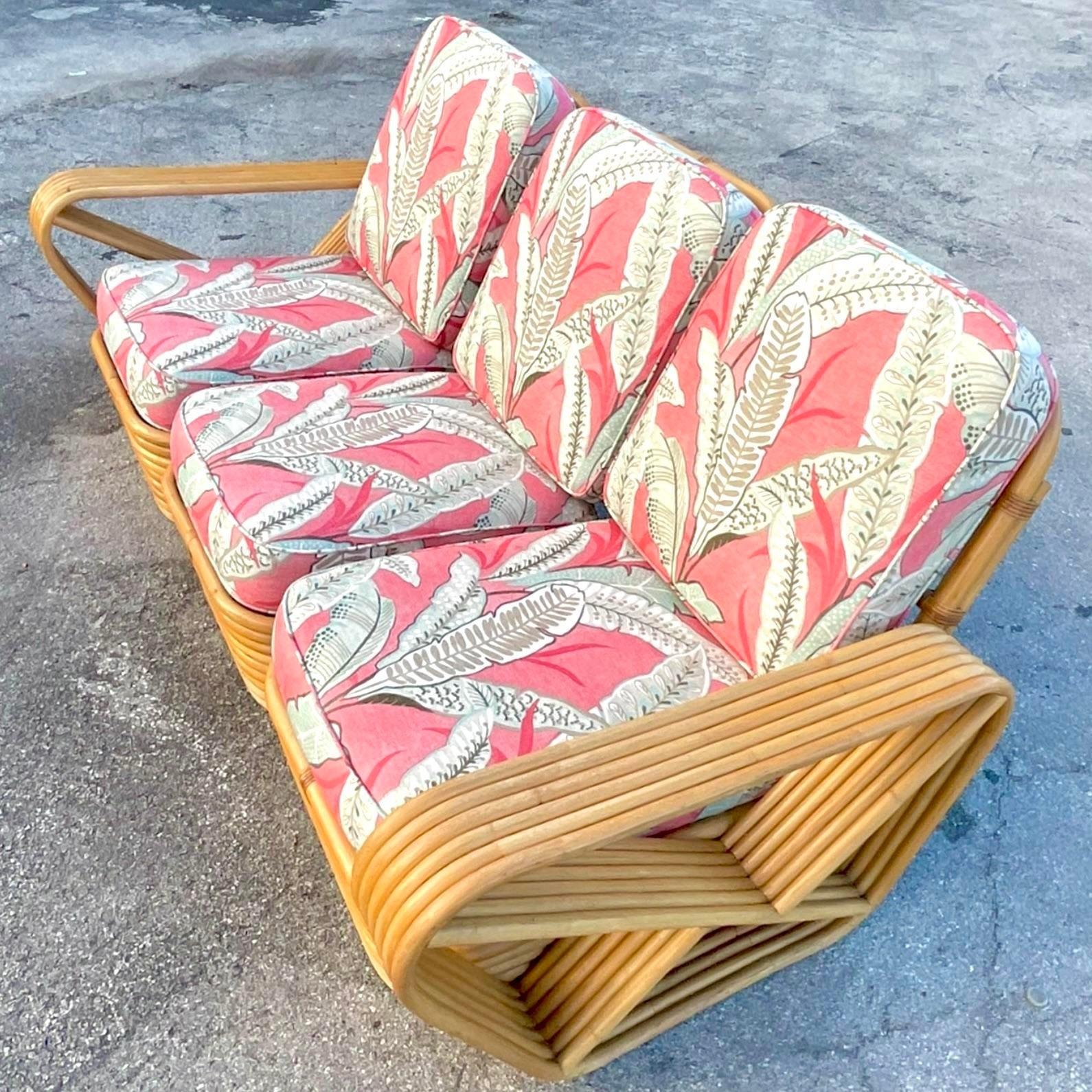 A fantastic vintage Coastal three seat sofa. A six strand rattan in the manner of Paul Frankl. Beautiful original cushions recently reupholstered. Acquired from a Palm Beach estate.