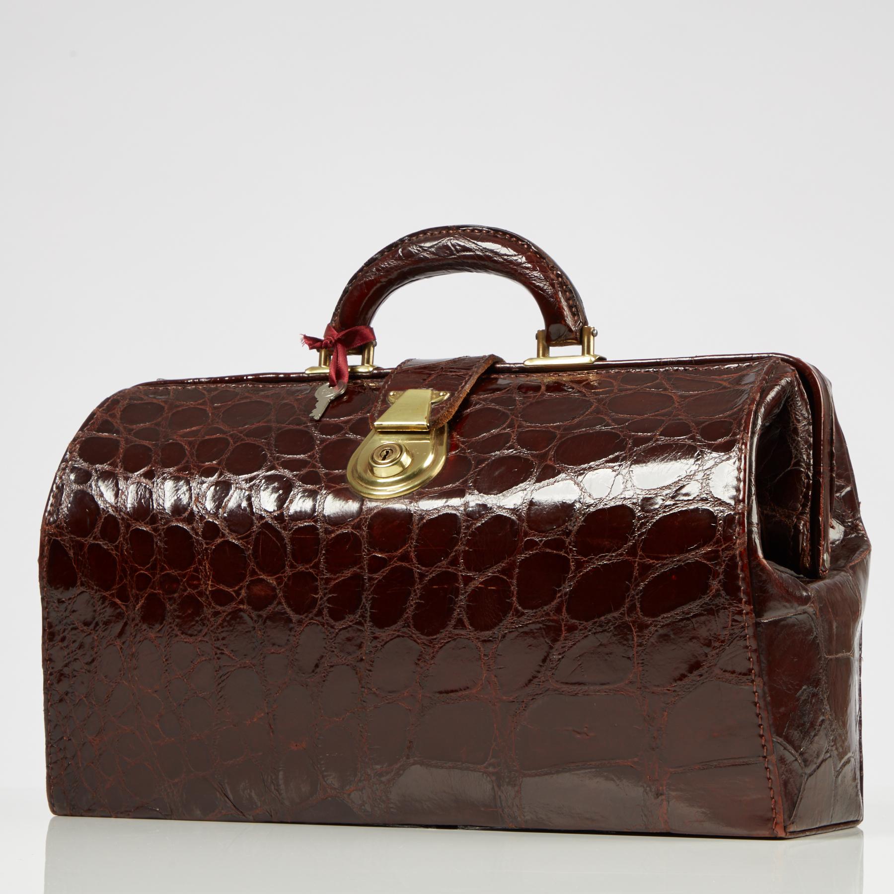 A wine color crocodile Gladstone bag complete with its original key.
Known as either a Gladstone bag or a doctors bag, it has been made in natural crocodile skin and is a deep ruby red in colour & the skin retains its original sheen.
You can tell