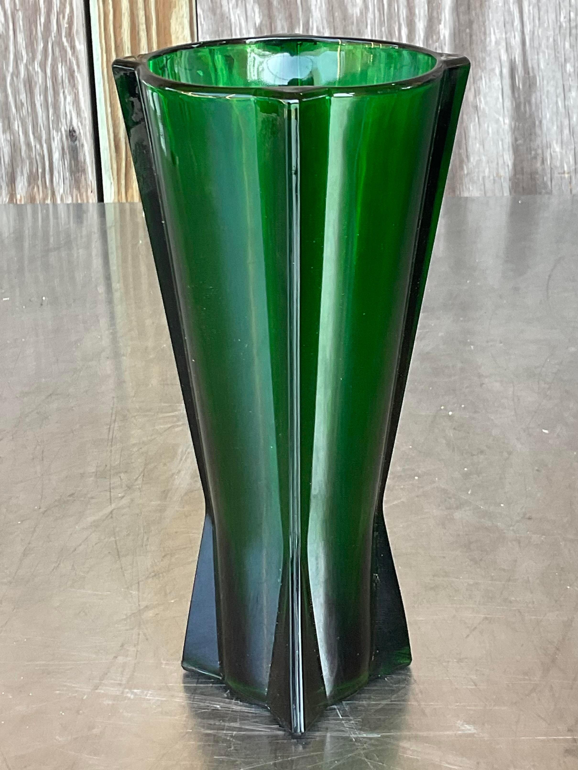 Diese grüne Glasvase im Vintage-Stil erinnert an die Eleganz des Art déco und strahlt zeitlose Raffinesse mit einem Hauch von amerikanischem Stil aus. Seine schlanke Silhouette und der satte Farbton machen ihn zu einem auffälligen Akzent für jeden