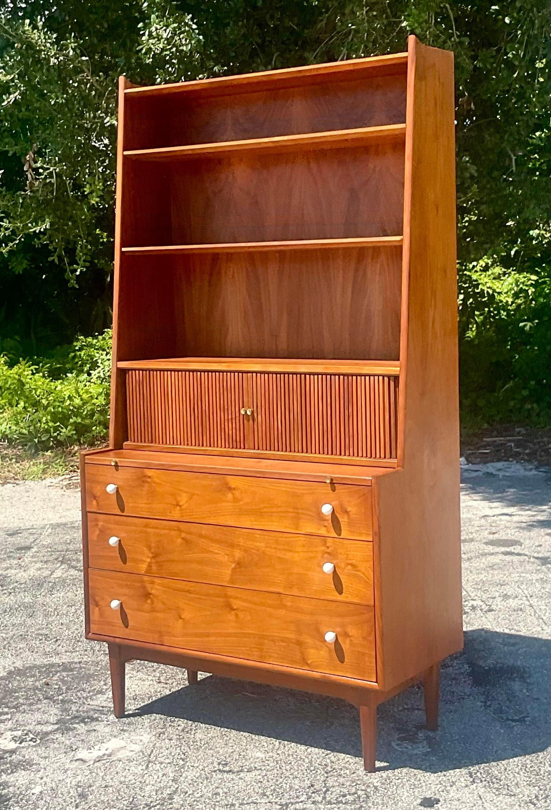 A fabulous vintage MCM secretary desk. Made by the iconic Drexel group and marked inside the drawer. A chic and streamlined design with a tapered upper cabinet. Sliding tam or doors reveal lots of great storage and flip top surface open for a desk.