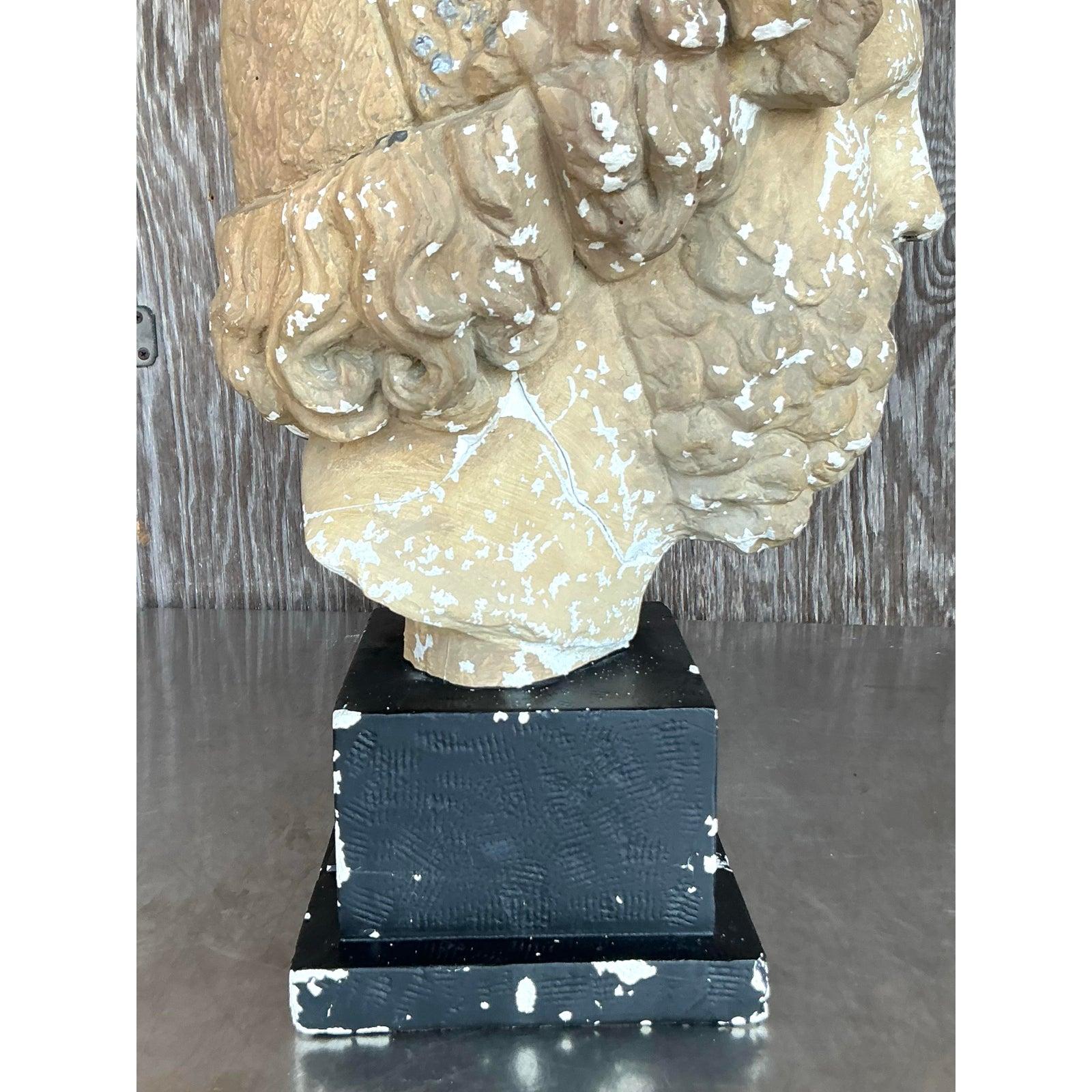 Incanala la grandezza classica nel tuo arredamento con questo imponente busto in gesso in stile Vintage Grand Tour di un uomo barbuto, che poggia su un piedistallo nero e consumato. Scolpito con dettagli drammatici, dai riccioli profondamente