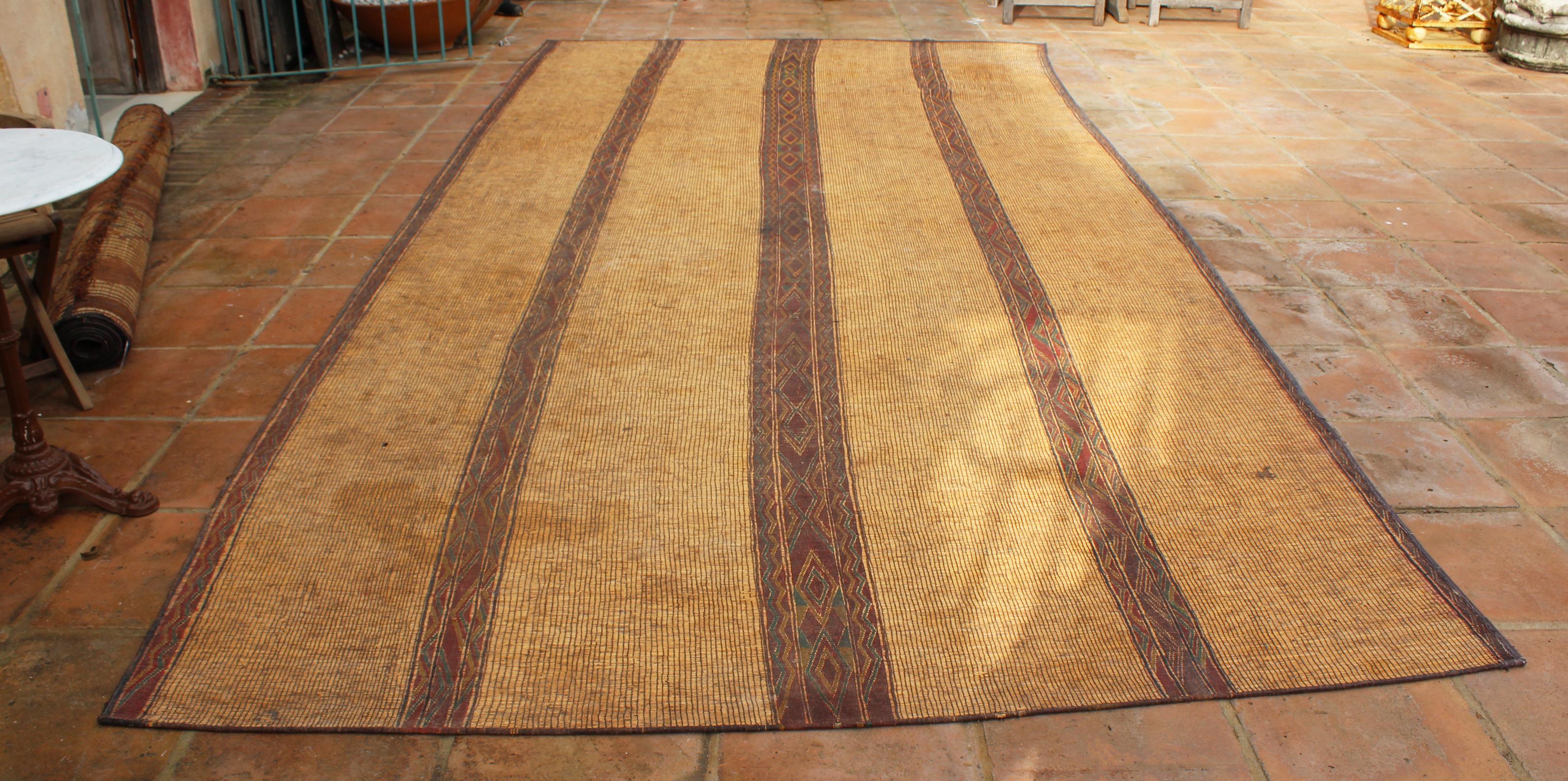 Moroccan Tuareg leather mats are made of dwarf palm tree fibers and hand woven with leather stripes, this are great to use indoor or outdoor, beautiful brown earth-tone colors. This vintage midcentury carpets are made in the desert of Morocco near