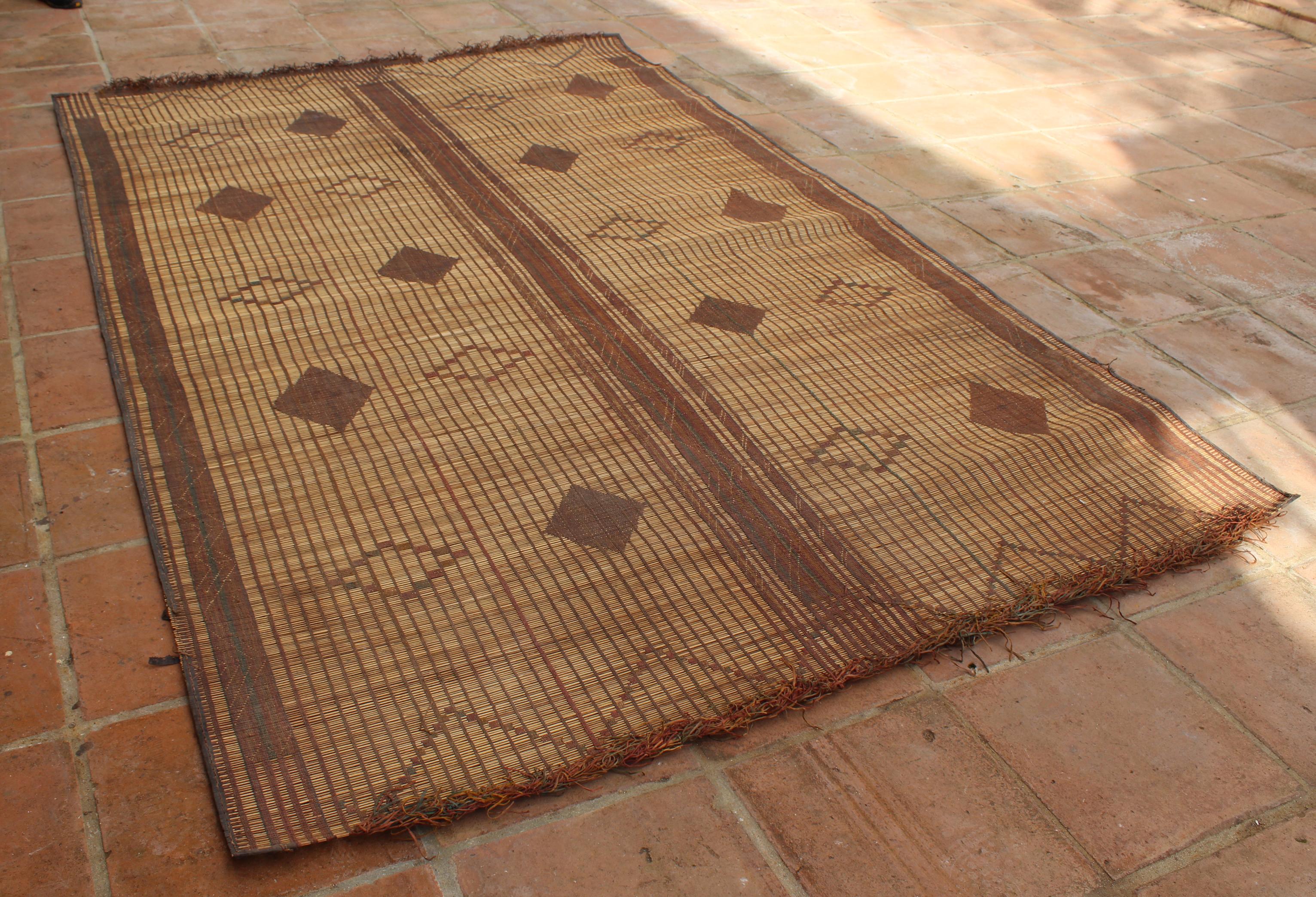 Mauritanian Tuareg leather mats are made of dwarf palm tree fibers and handwoven with leather stripes, this are great to use indoor or outdoor, beautiful brown earth-tone colors. This vintage midcentury carpets are made in Mauritania and have the