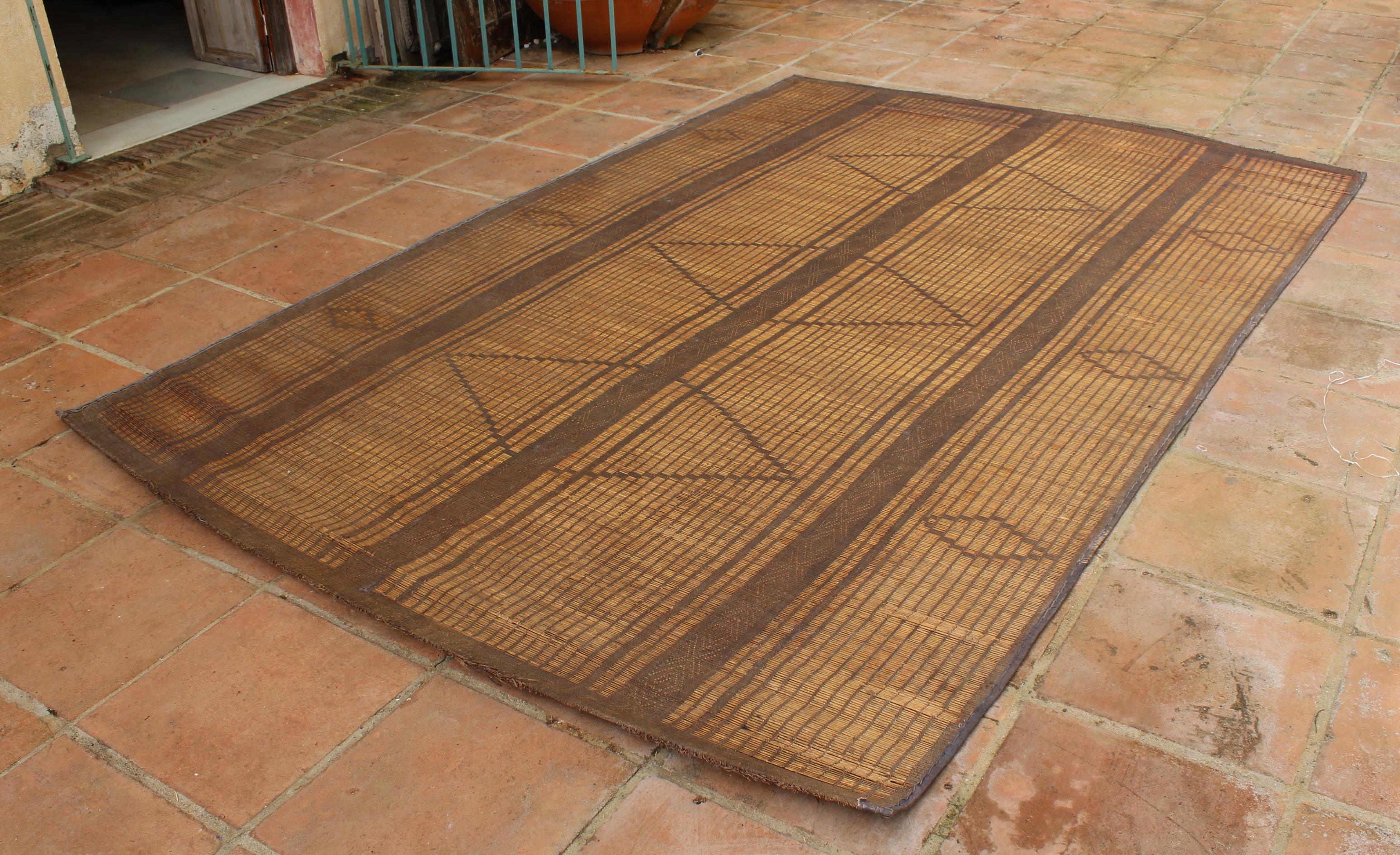 Moroccan Tuareg leather mats are made of dwarf palm tree fibers and hand woven with leather stripes, this are great to use indoor or outdoor, beautiful brown earth-tone colors. This vintage midcentury carpets are made in the desert of Morocco near